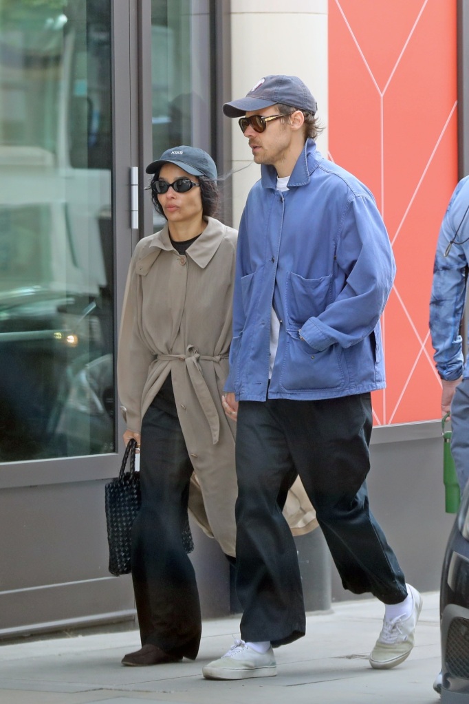 Zoe Kravitz and Harry Styles walking outdoors, both wearing hats and sunglasses.