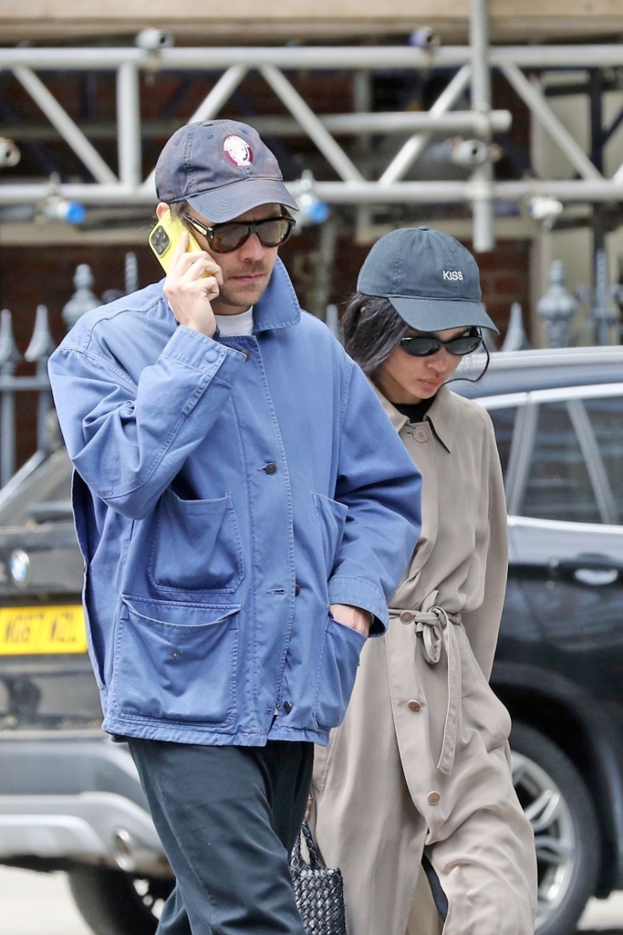 Harry Styles on the phone, walking beside Zoë Kravitz, who is wearing a baseball cap with 