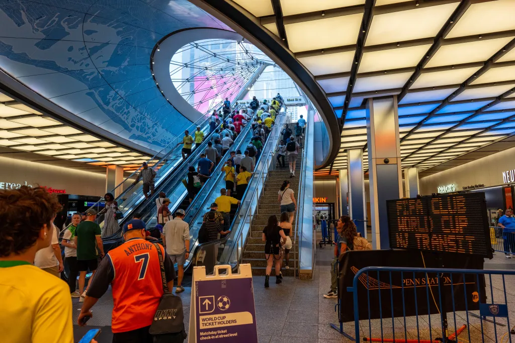 World Cup ticket holders at Penn Station walking up escalators.