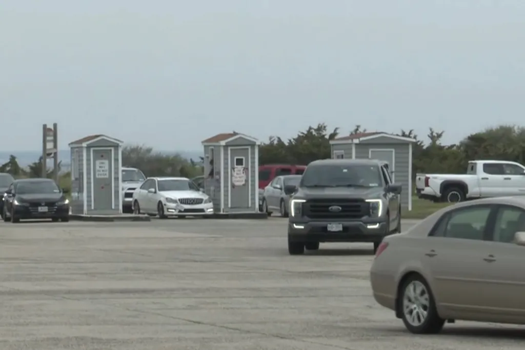Cars driving through booths in a parking lot.