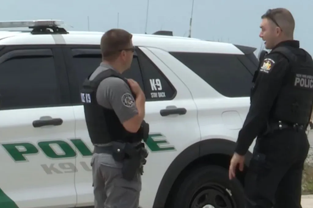 Two police officers standing next to a K-9 unit patrol car.