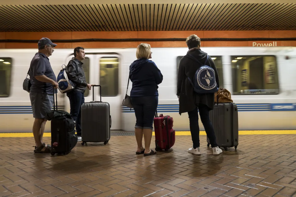 Travelers with luggage wait for a Bay Area Rapid Transit (BART) train at Powell Street station.