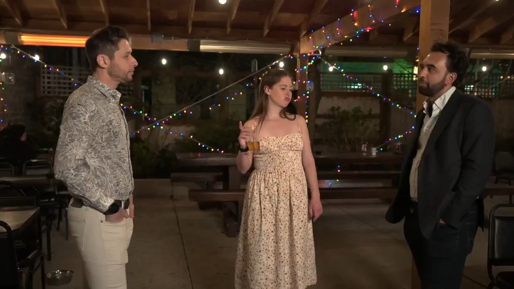 Catie with a drink in hand standing between Josh and another man.