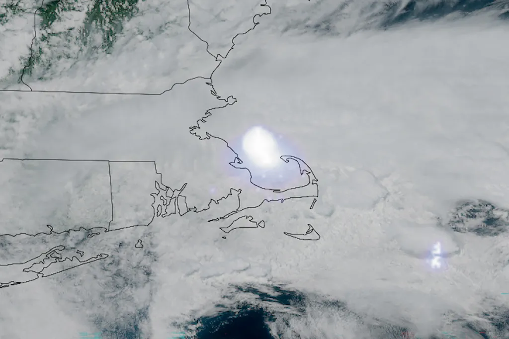 Satellite image of a large cloud system covering New England, with a bright flash of lightning over Massachusetts.