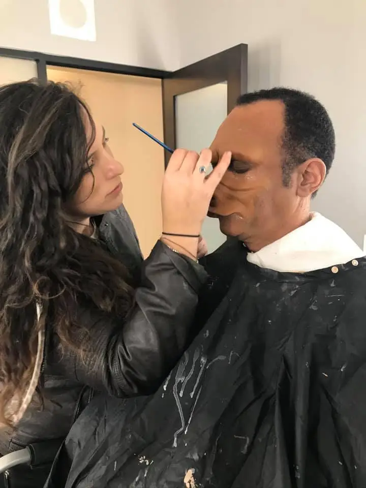 Allie Shehorn applying makeup to an actor.