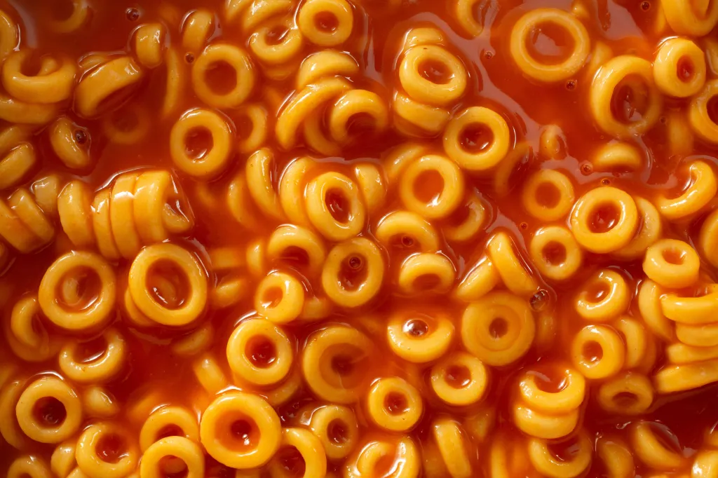 Close-up overhead view of Spaghettio's, a canned pasta consisting of ring-shaped pasta in tomato sauce.