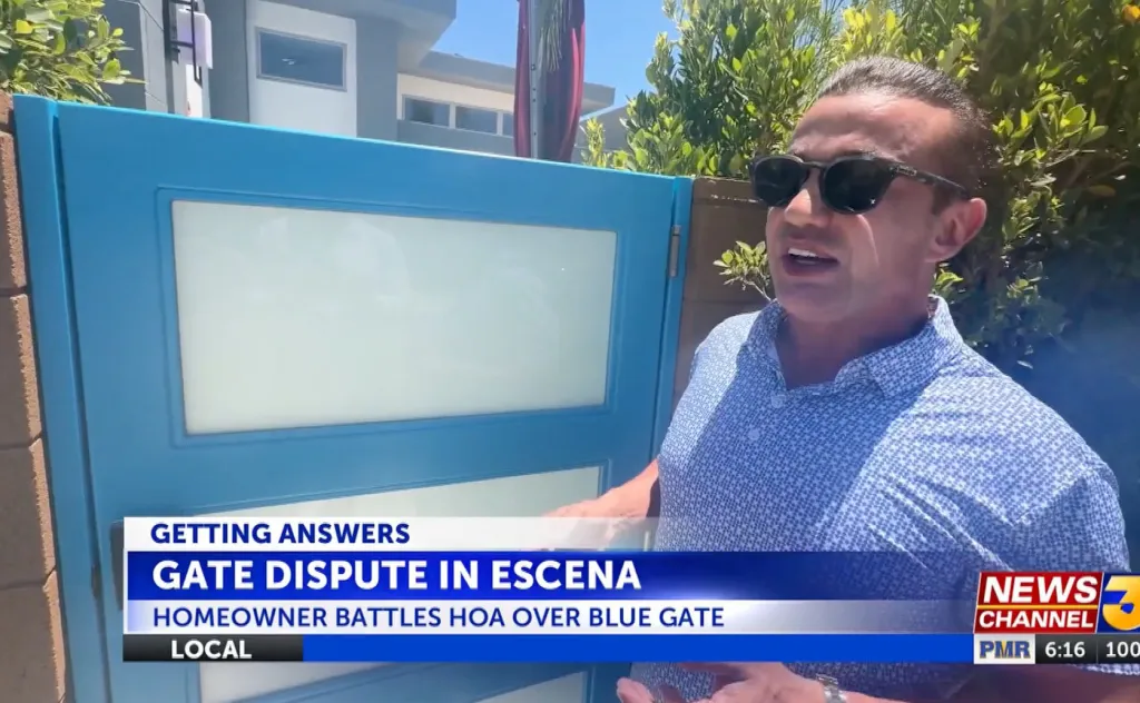 A man in sunglasses standing next to a blue gate, with news captions about a 