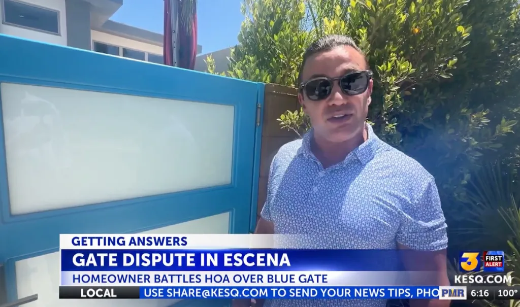 Man in sunglasses standing in front of a blue gate with news text 
