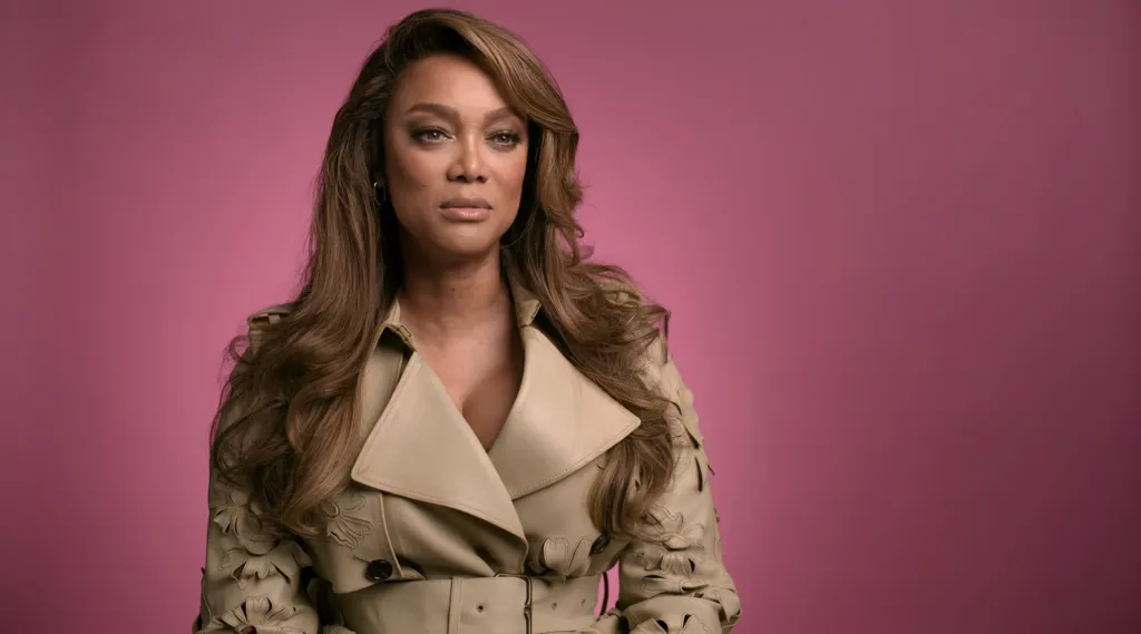 Tyra Banks wearing a tan leather trench coat.