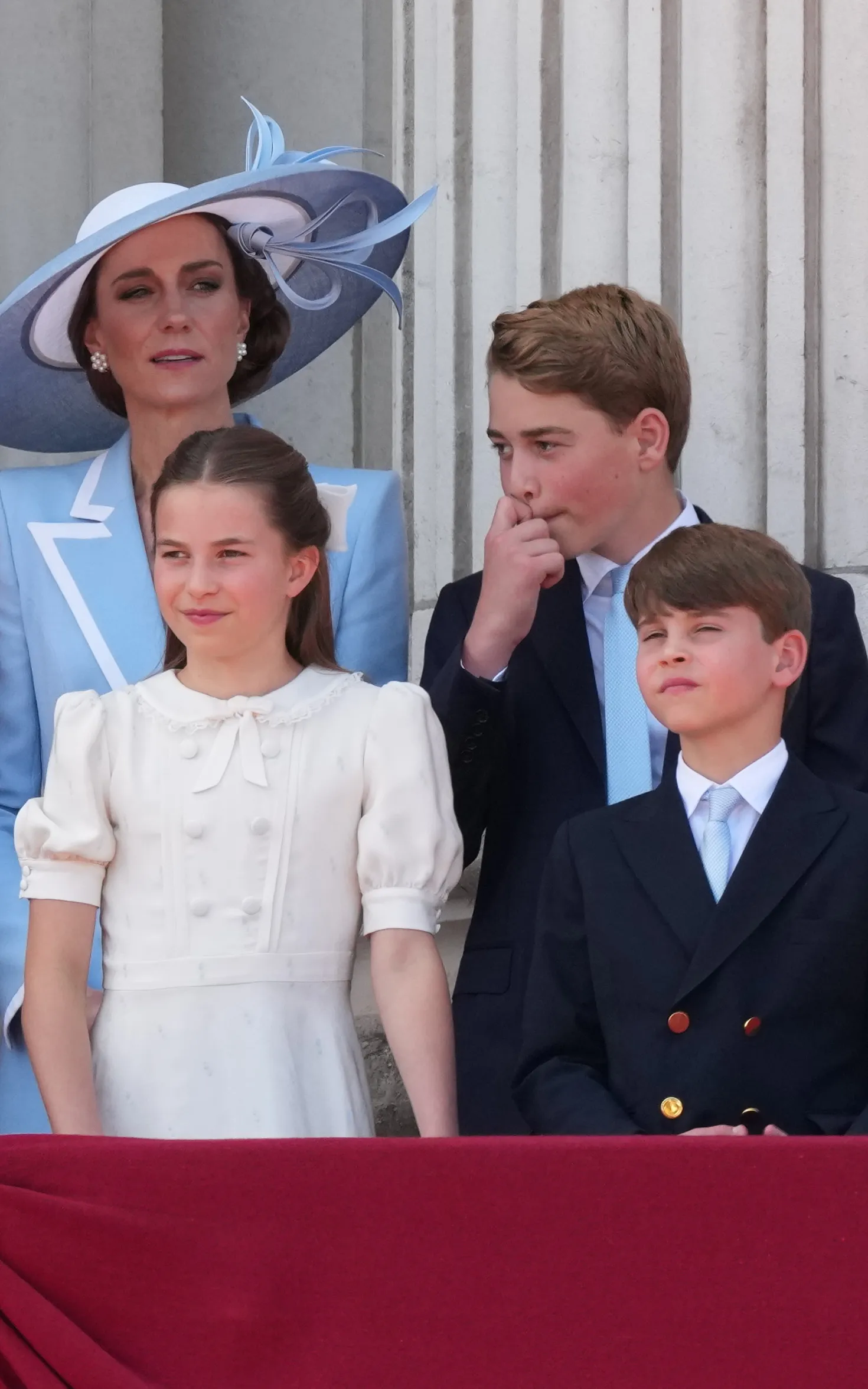 Kate Middleton, Princess Charlotte, Prince George, and Prince Louis watching an event from a balcony.
