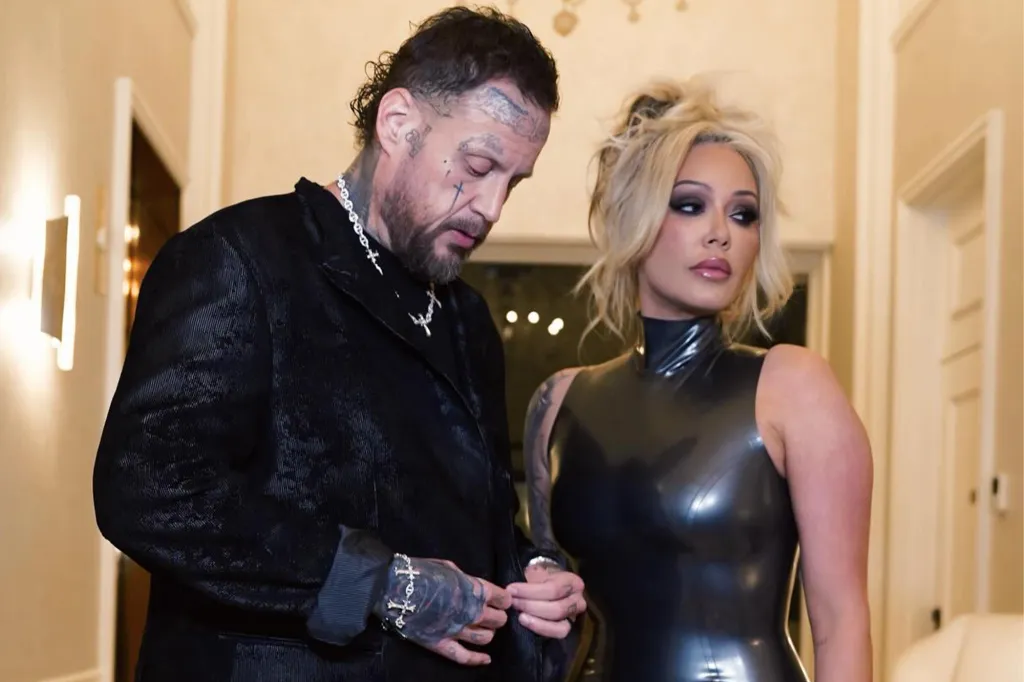 Mod Sun and Avril Lavigne pose together, with Mod Sun in a black blazer and chains, and Avril Lavigne in a black latex dress.
