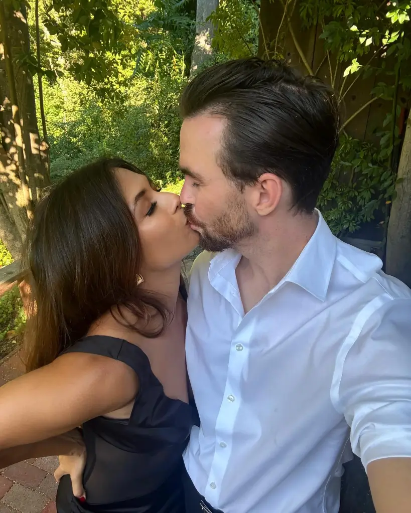 A man and a woman in formal wear kissing outdoors.