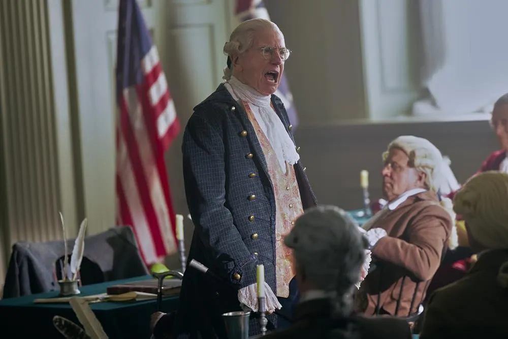 An actor in historical costume and wig portraying a Founding Father speaking forcefully.