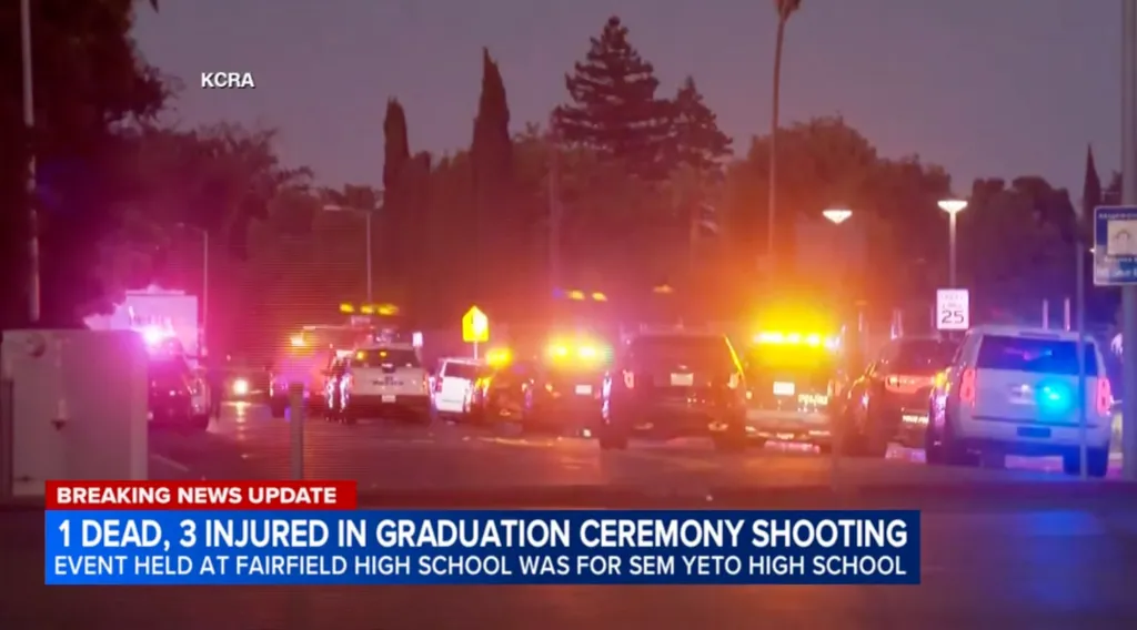 Police and emergency vehicles with flashing lights at the scene of a graduation ceremony shooting.