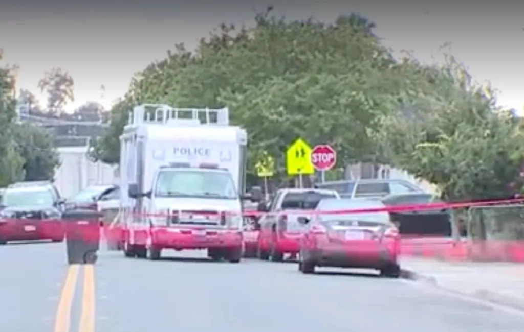 Police vehicles and crime scene tape block off a street.