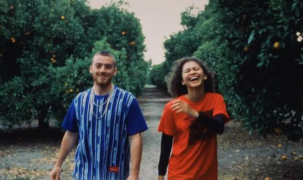 Two young people, a man and a woman, walking together in an orchard.