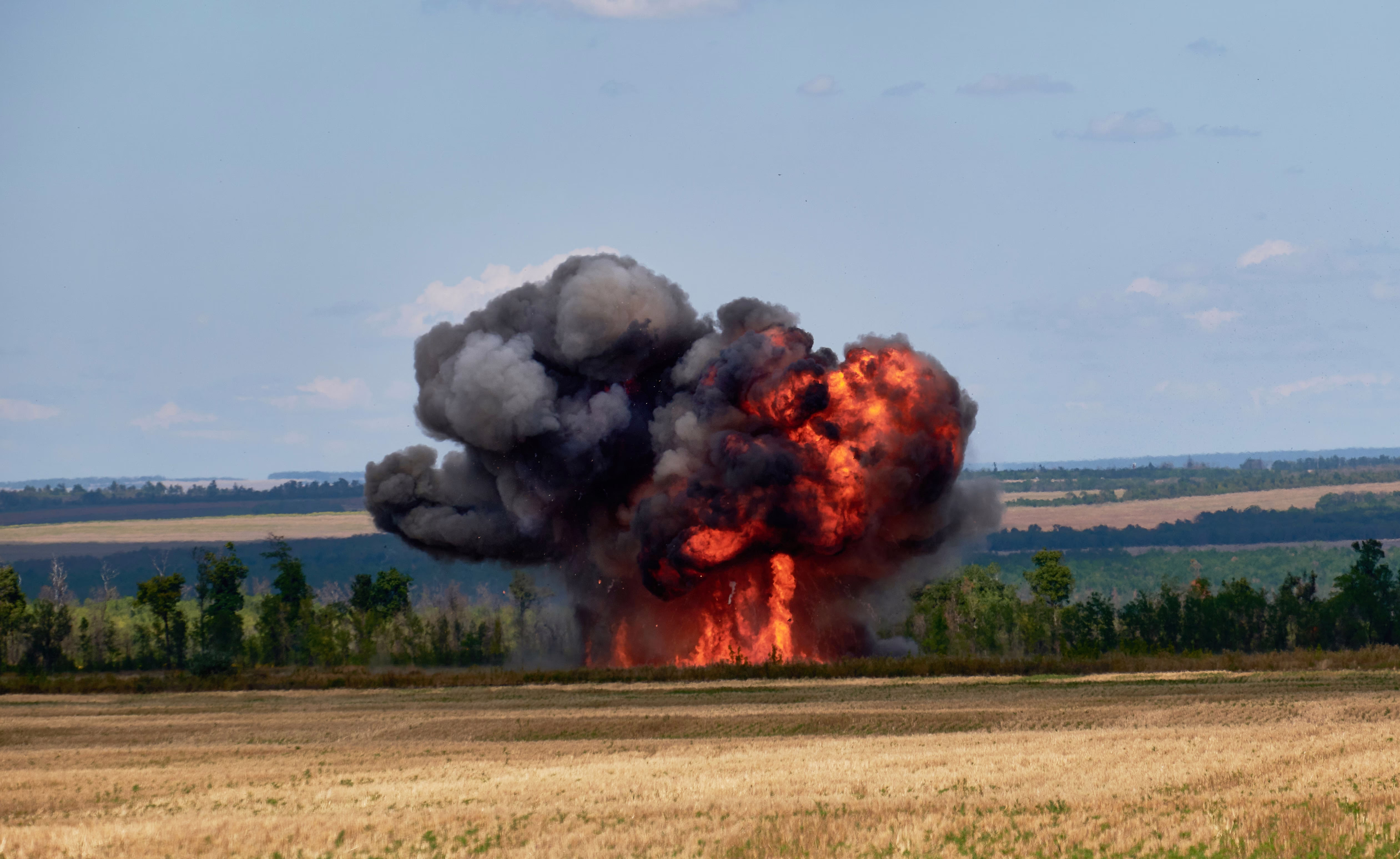 A fiery explosion, seen beside a farm field