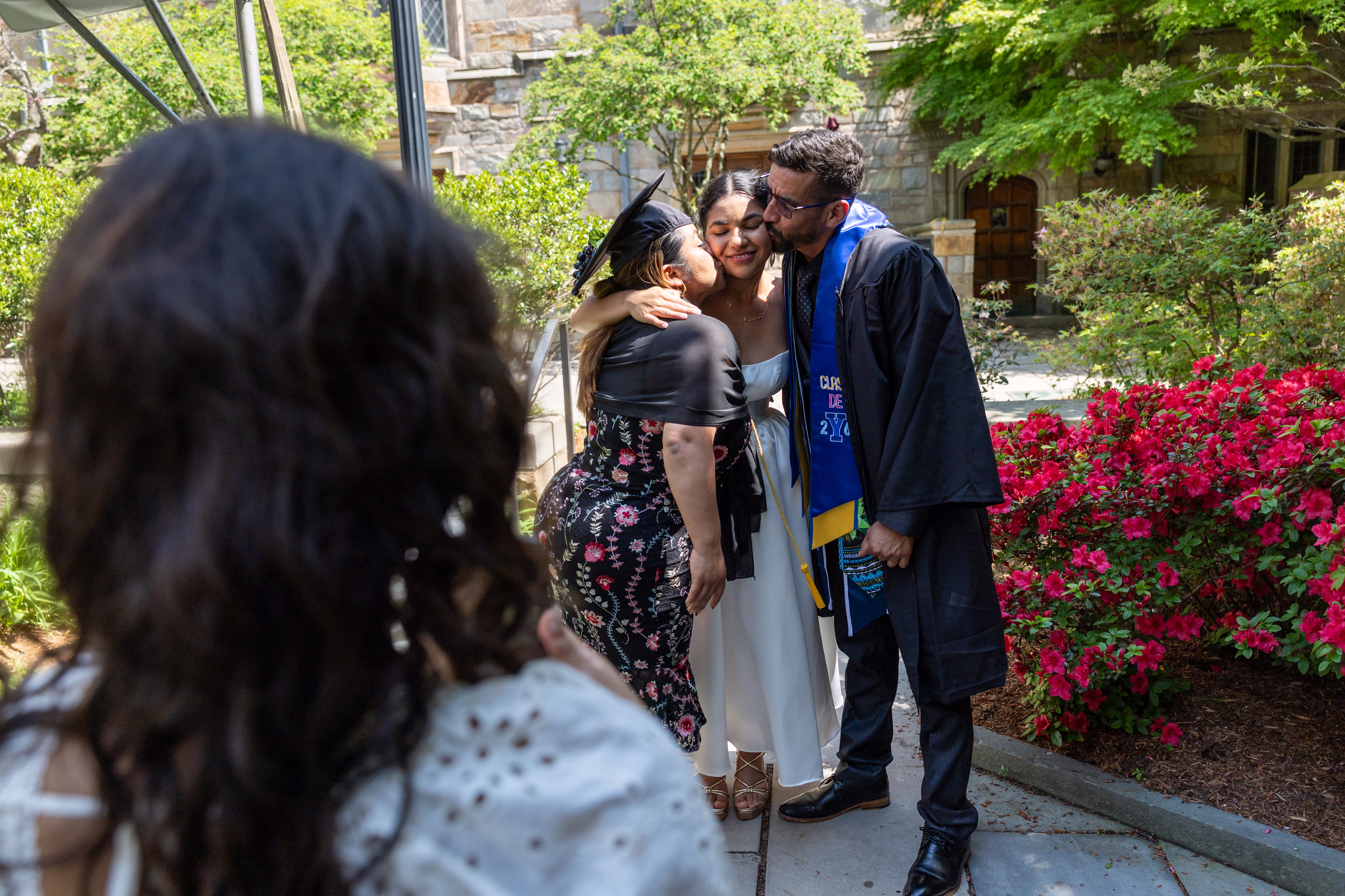 A young woman poses with her parents after her graduation ceremony.