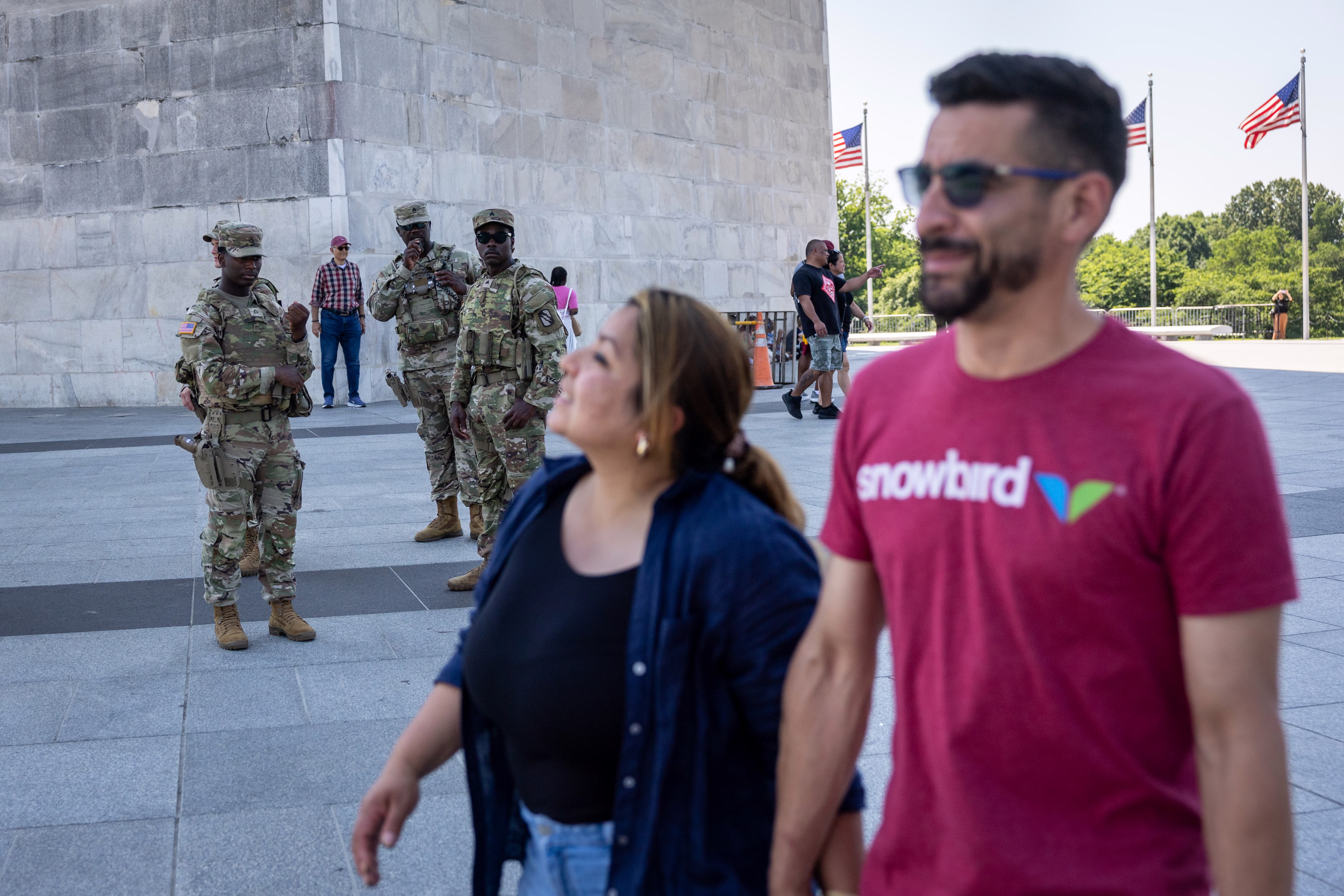 Several National Guard soldiers look on as tourists walk past the Washington Monument.