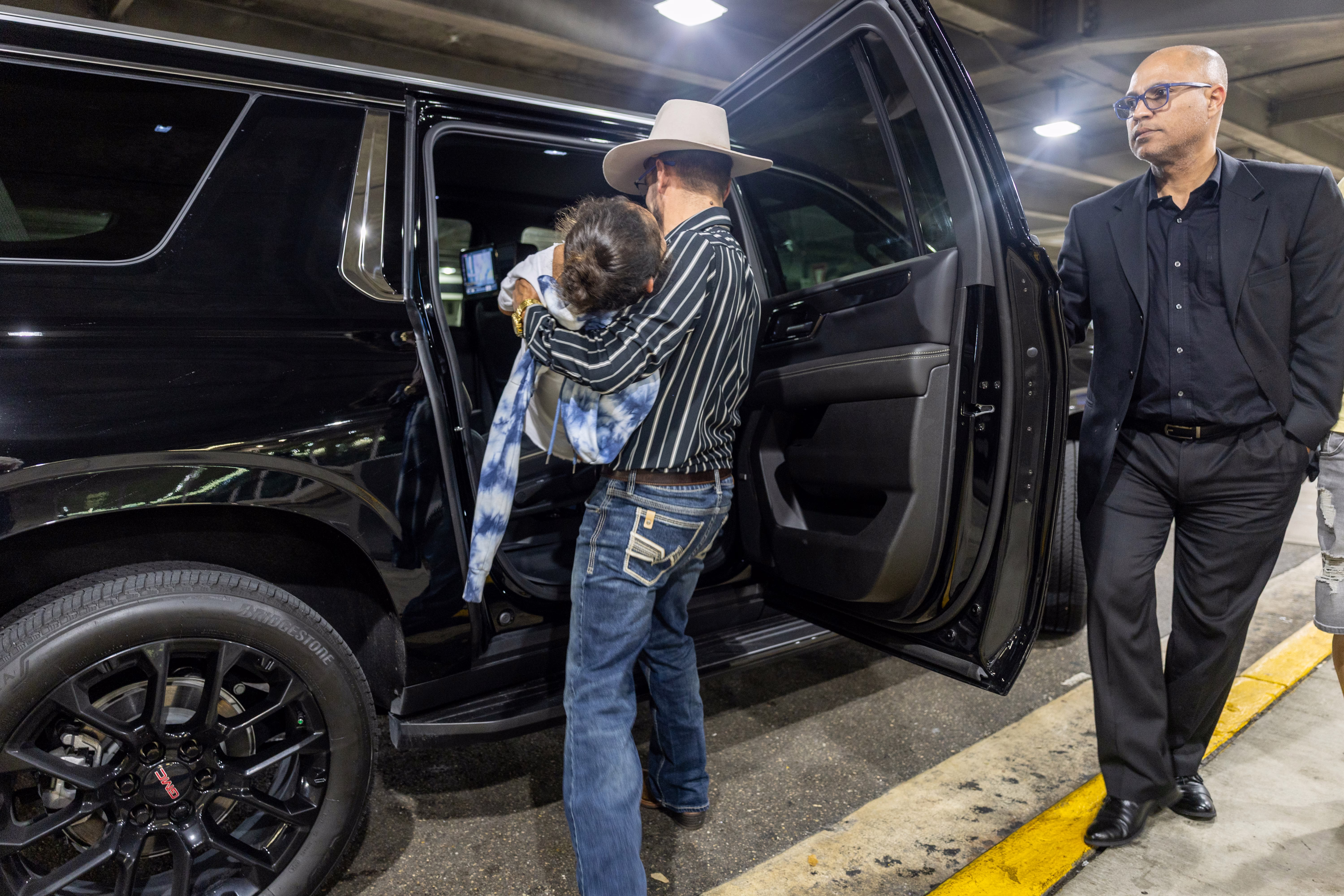 A father holds his young daughter while placing her in a car.