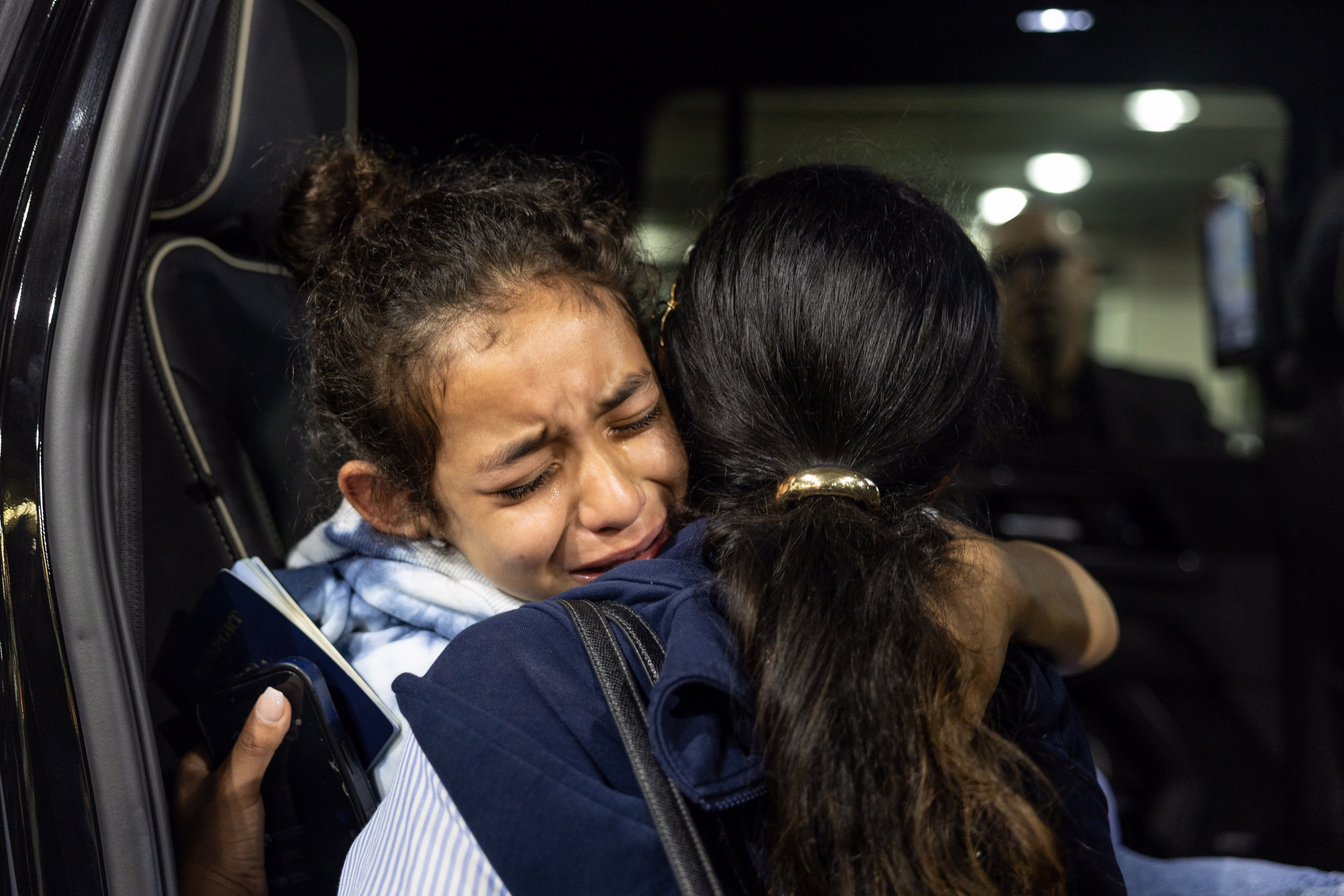 A distraught girl is comforted by her big sister.