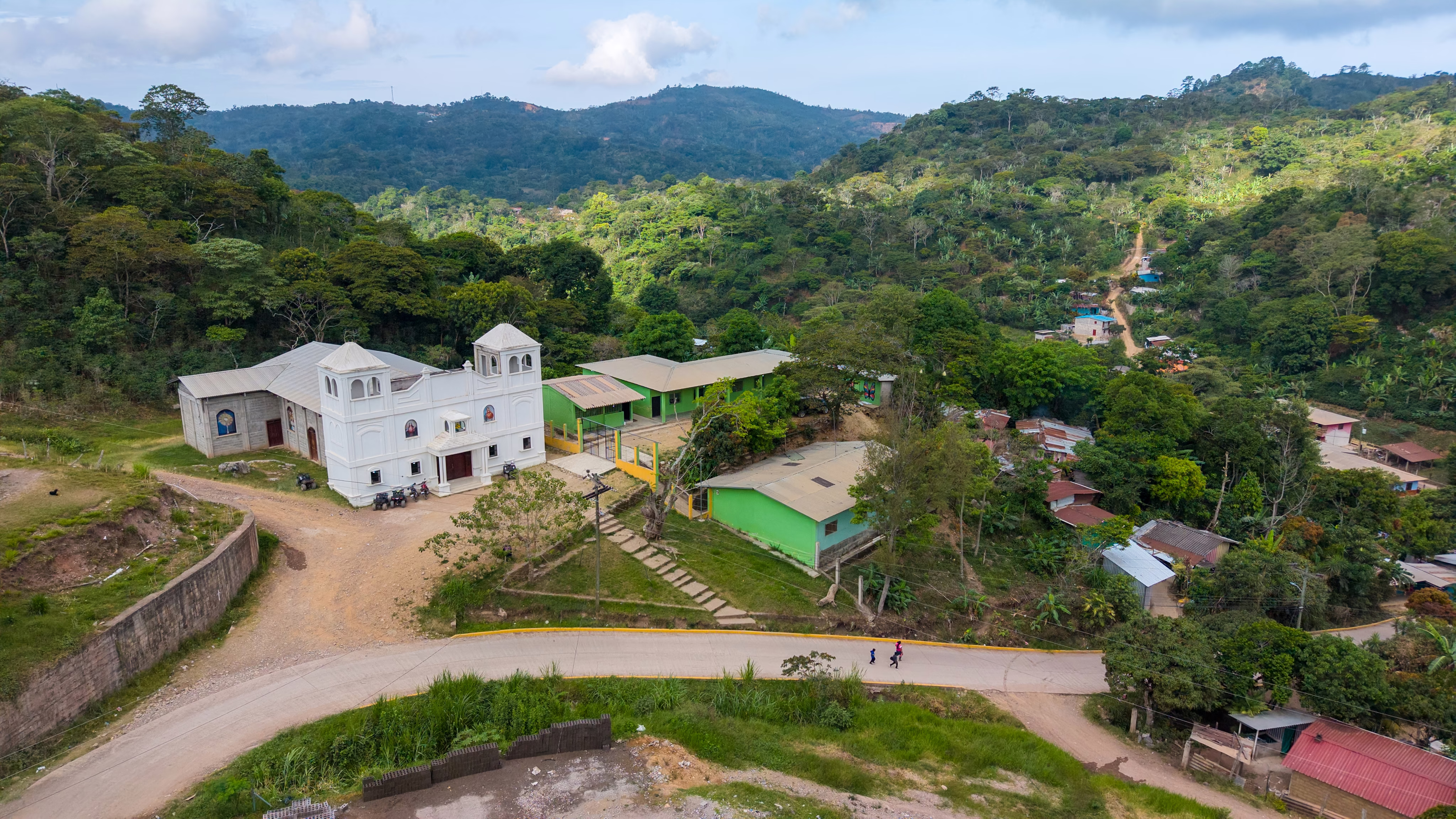 An aerial view of a Catholic church in a hillside Honduran village