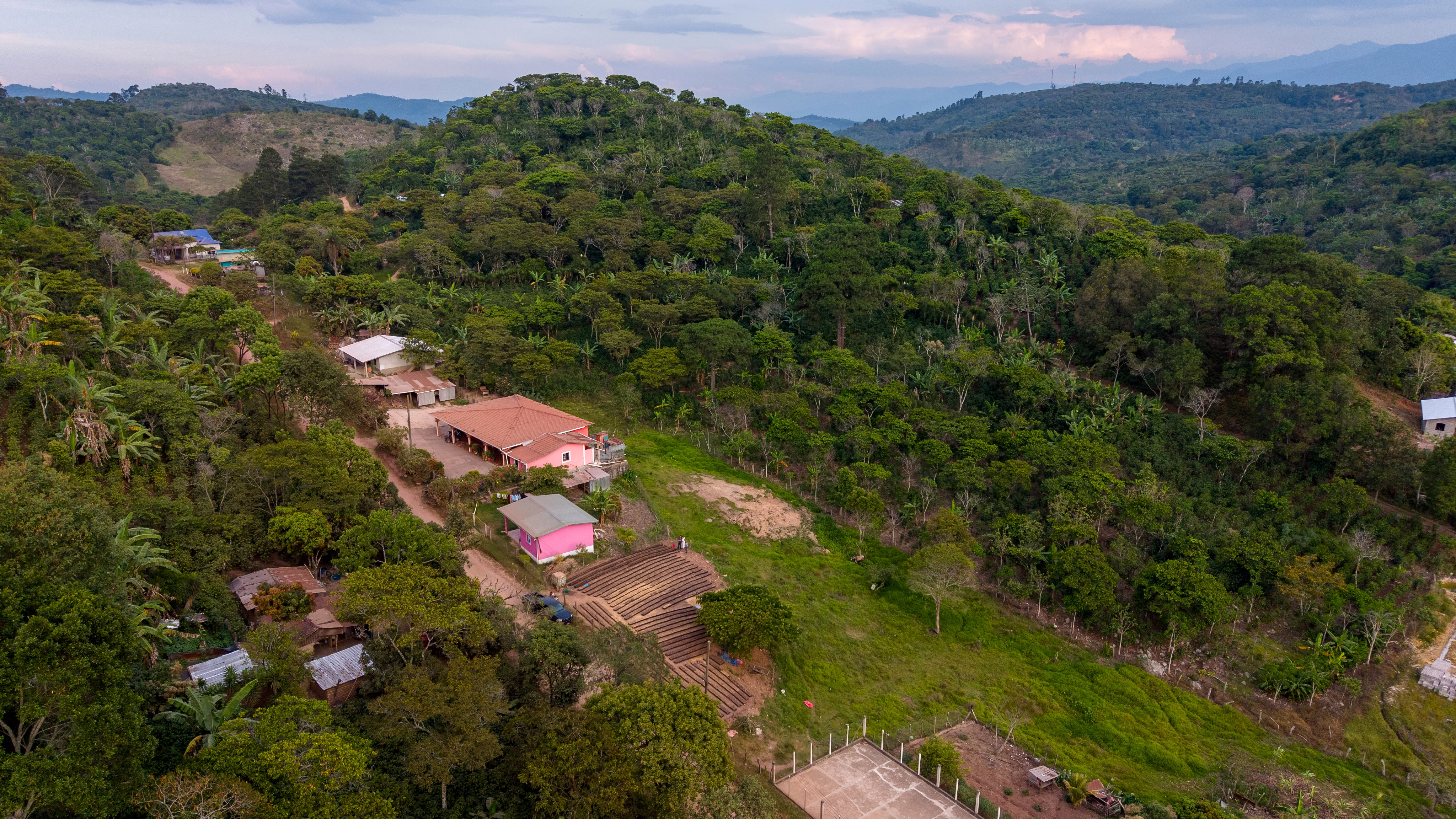 An aerial view of small farms in a village in a hilly, forested area in Honduras