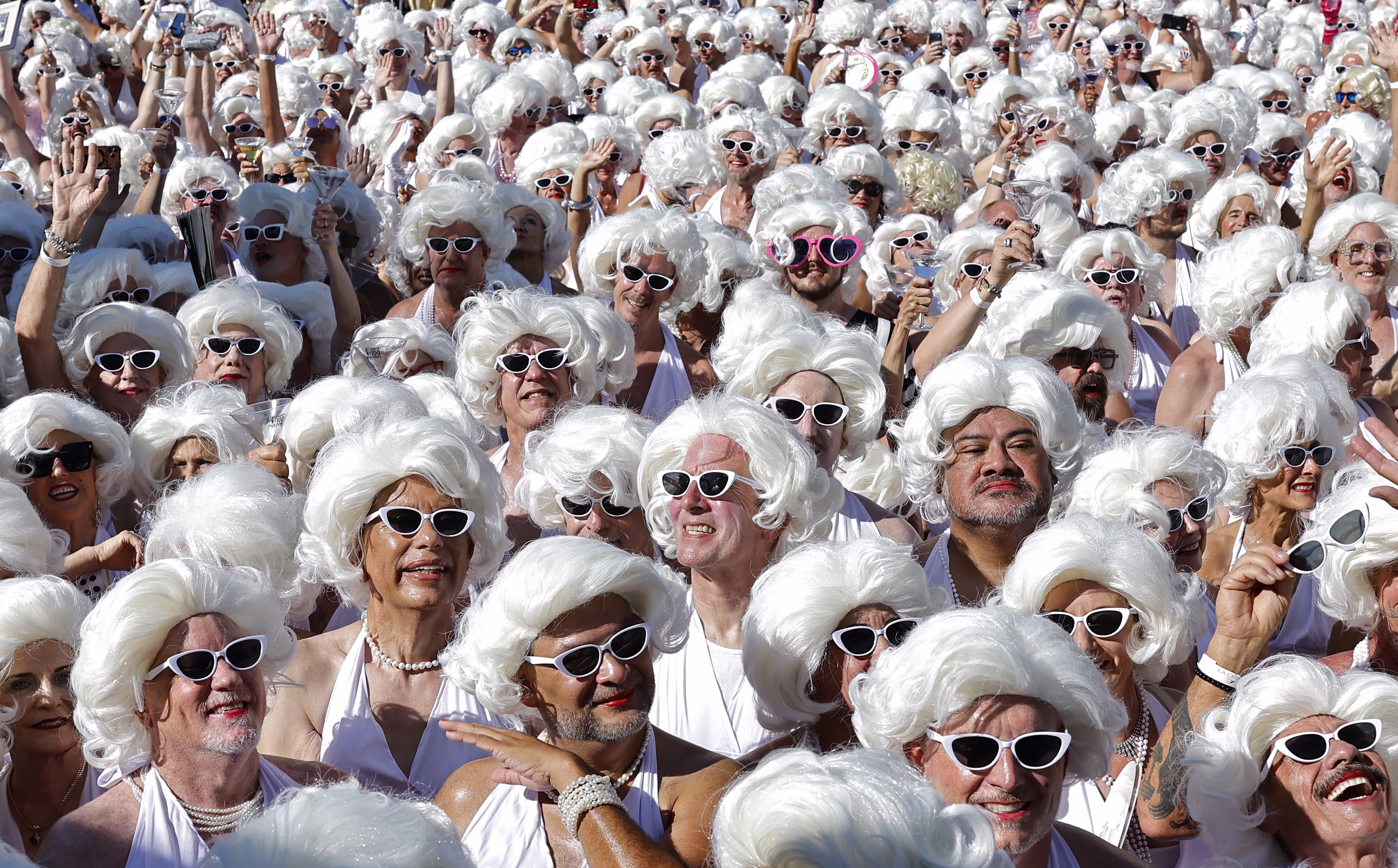 A crowd of dozens of people dressed as Marilyn Monroe, wearing white wigs and sunglasses