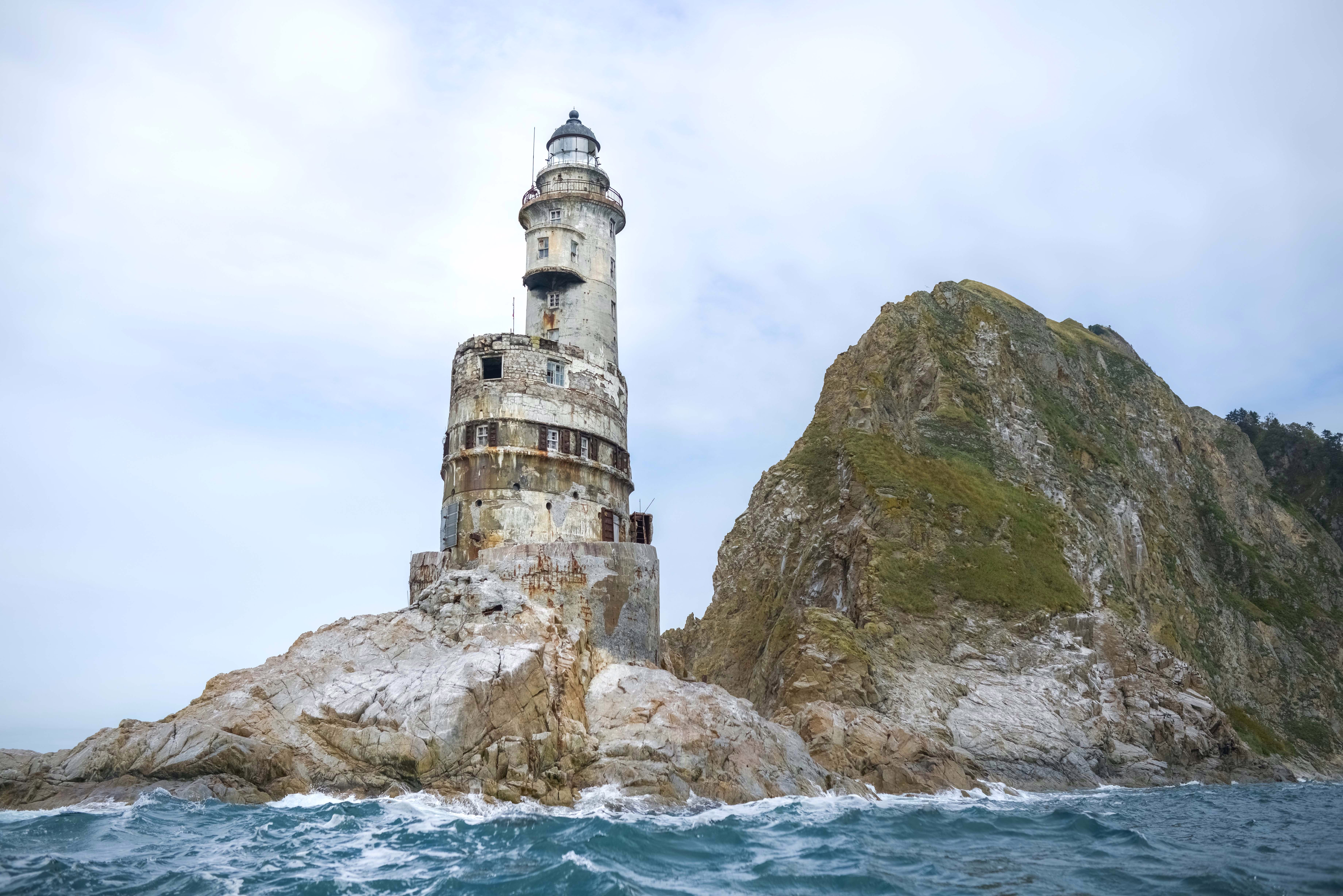 A crumbling, abandoned lighthouse, built onto a rocky cliff