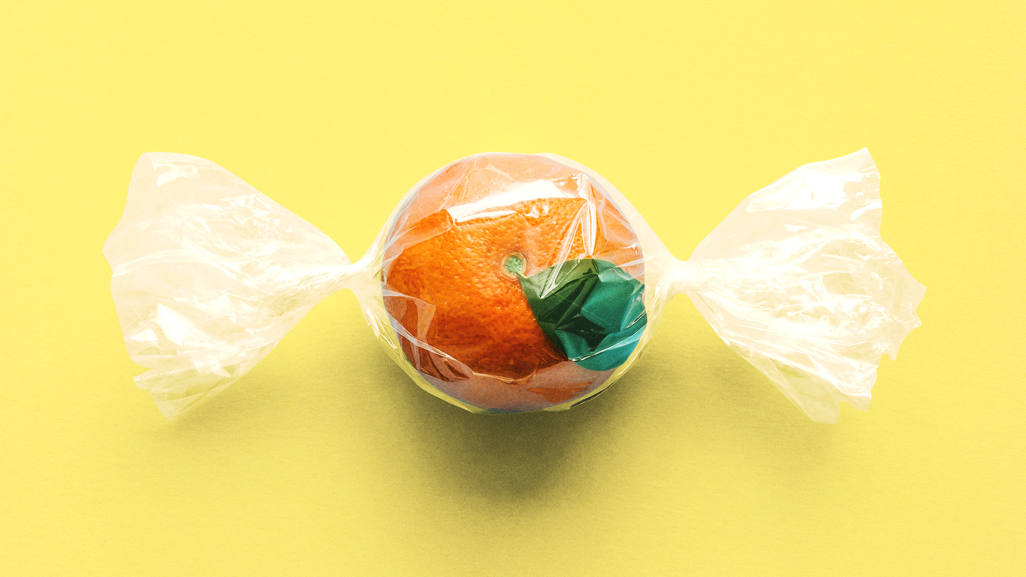 An orange is wrapped in plastic like candy