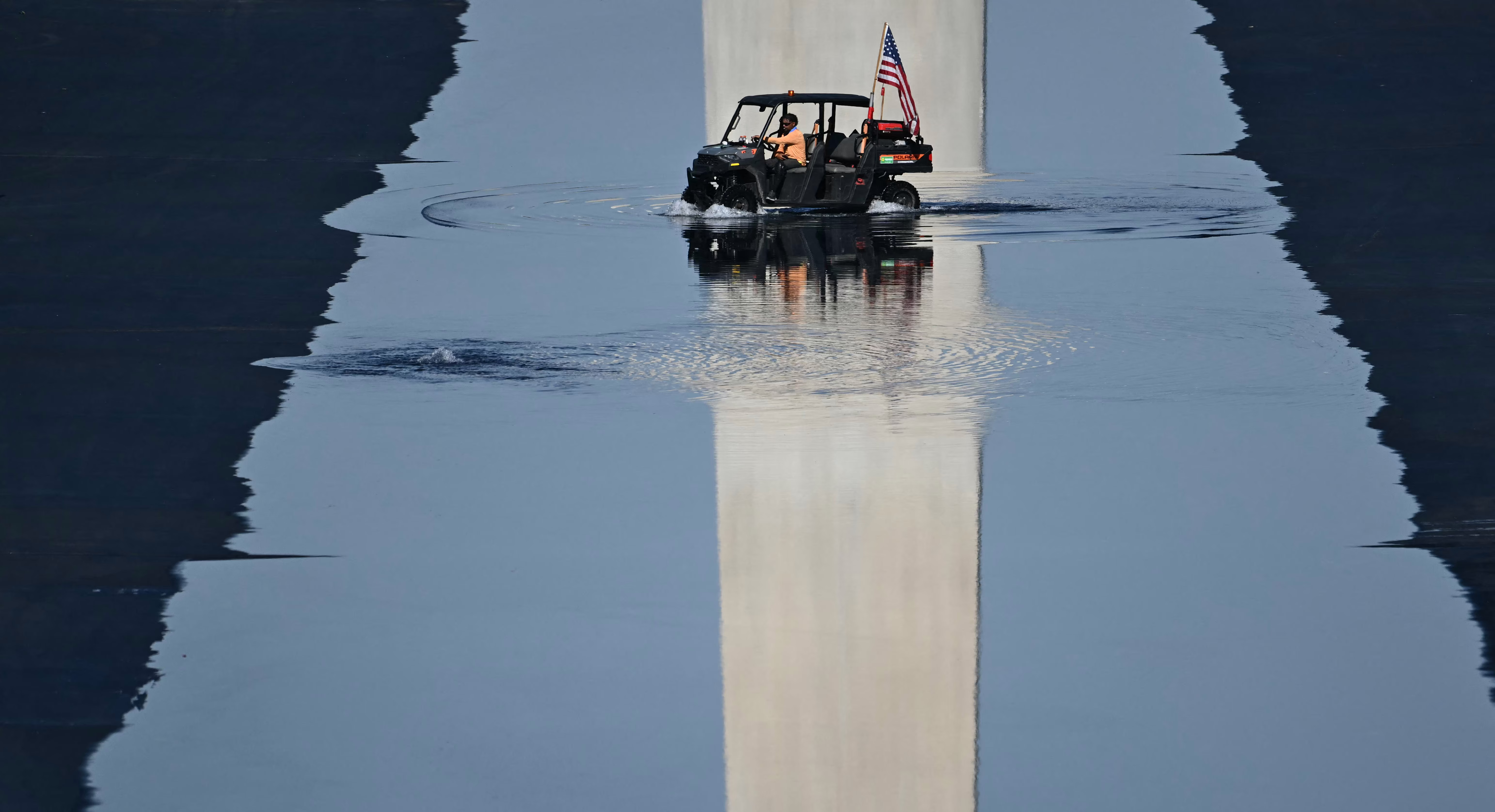 Contractors drive a small vehicle in the partially-filled Lincoln Memorial Reflecting Pool.