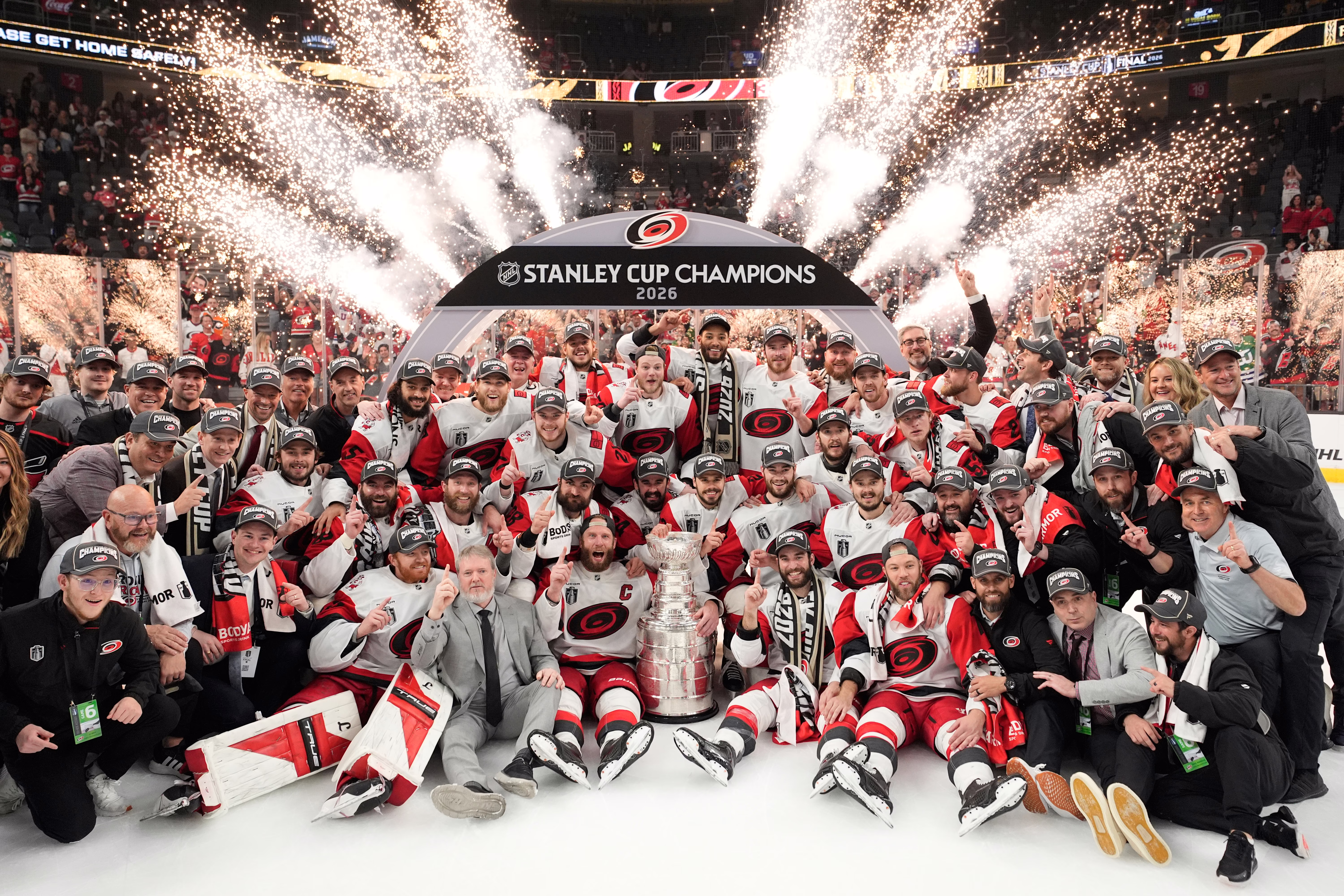 A hockey team and its coaching and support staff pose on the ice after winning the Stanley Cup.