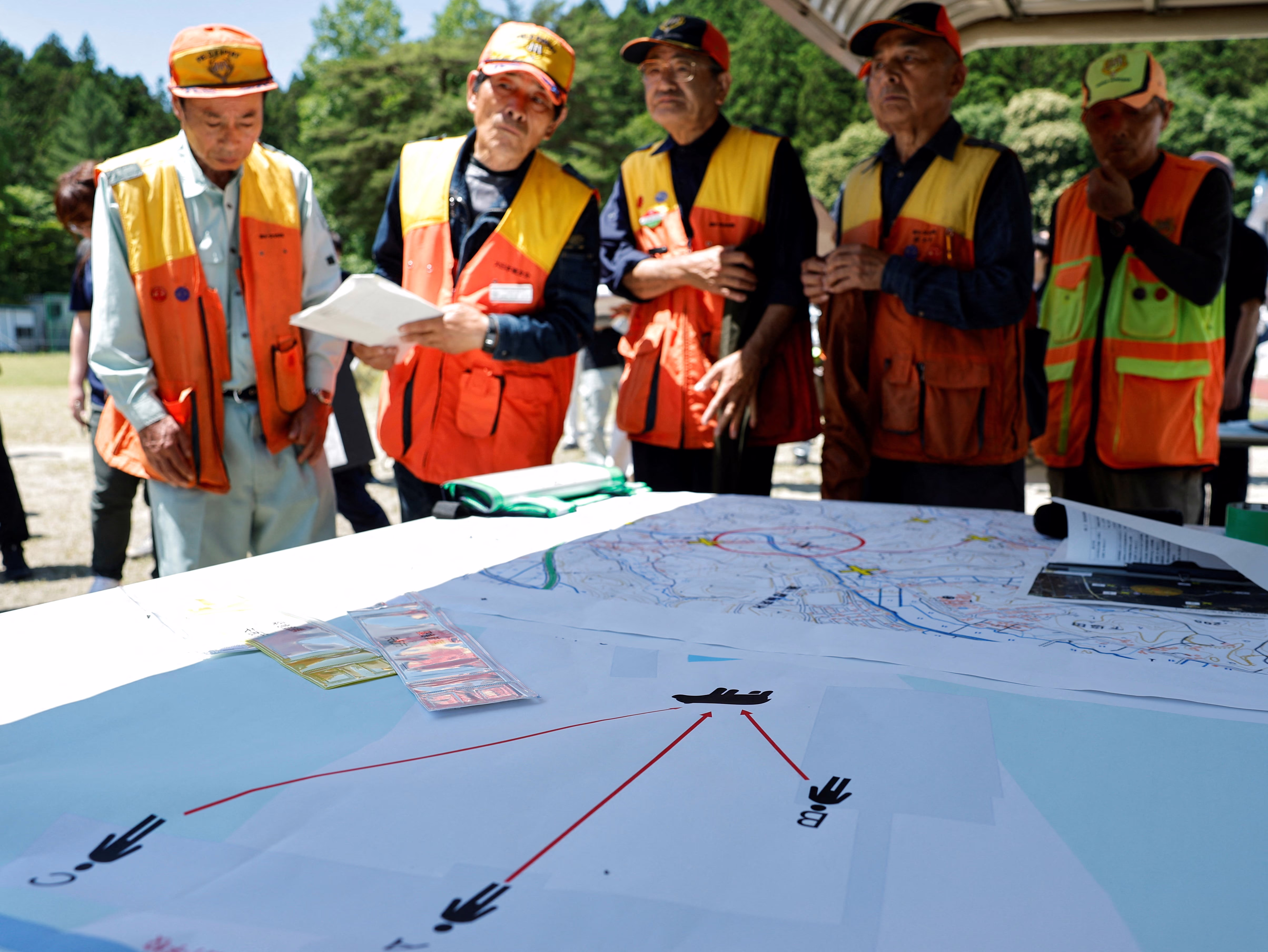 Hunters wearing hi-viz vests look at a map and diagram.