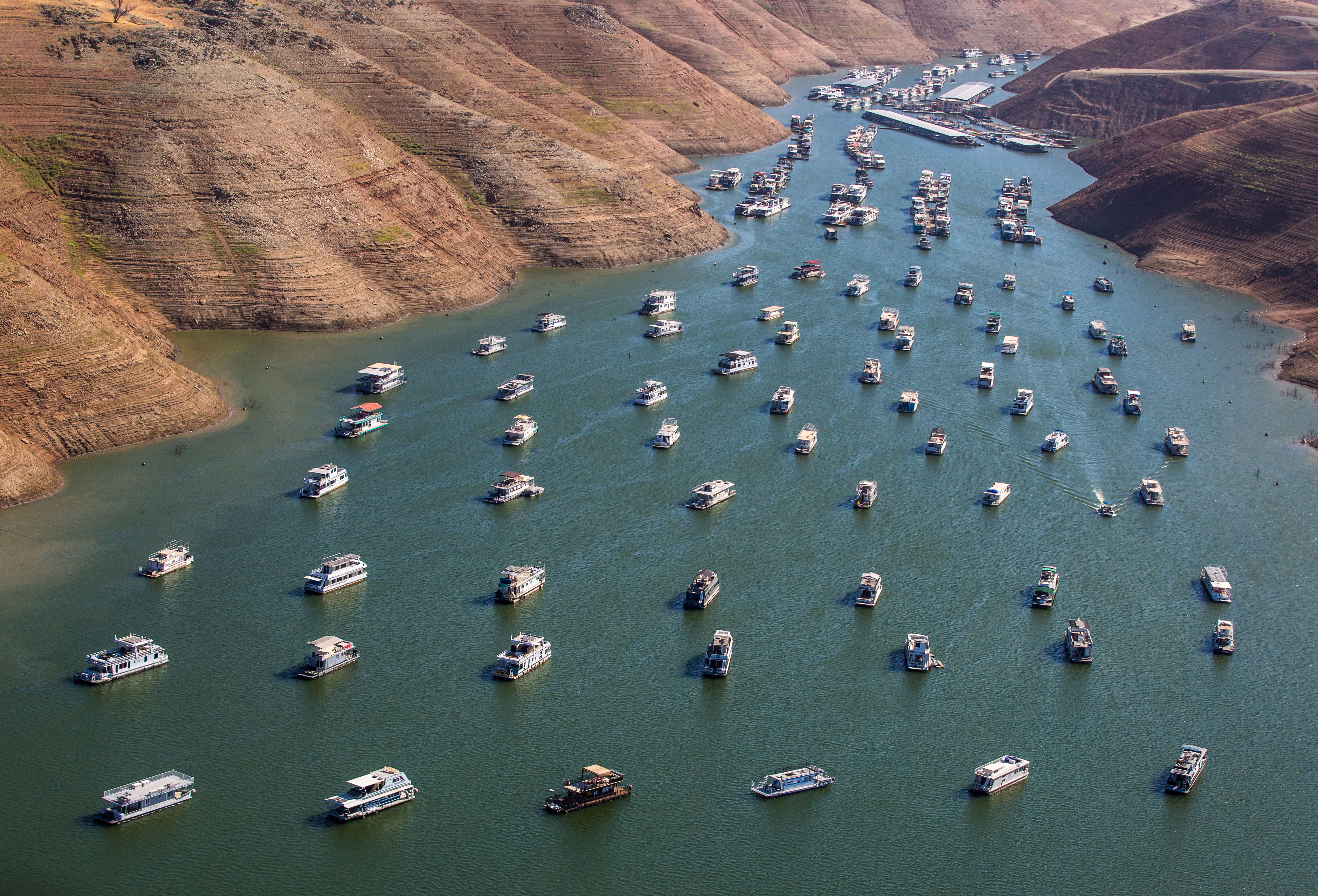Many boats, moored in a reservoir at low-water levels
