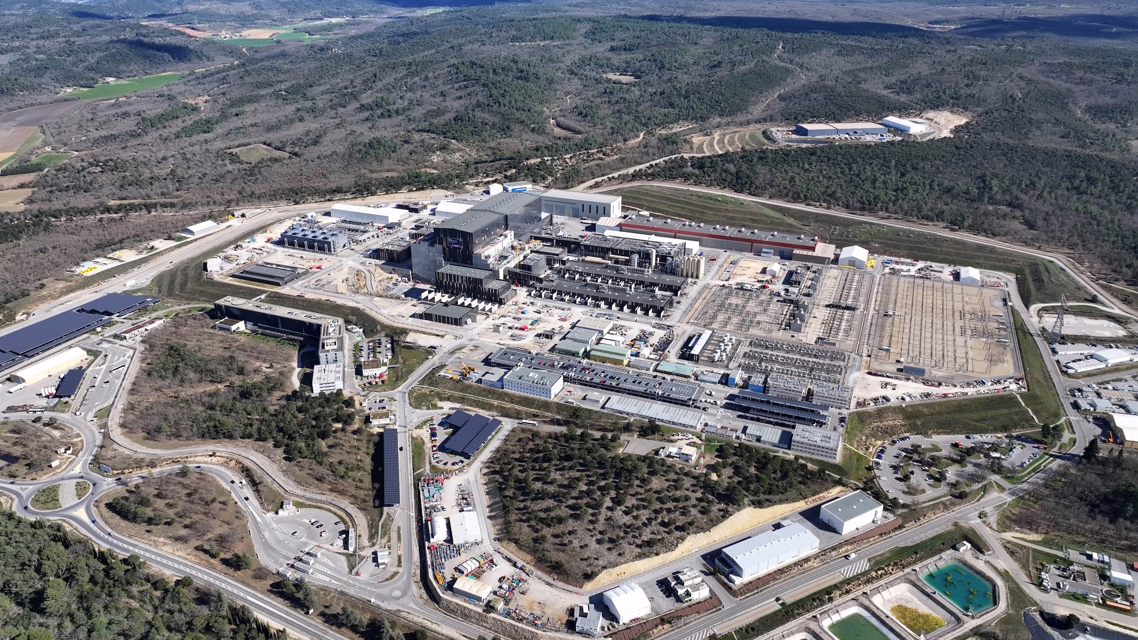 An aerial view of a sprawling complex of large and small buildings and electrical infrastructure