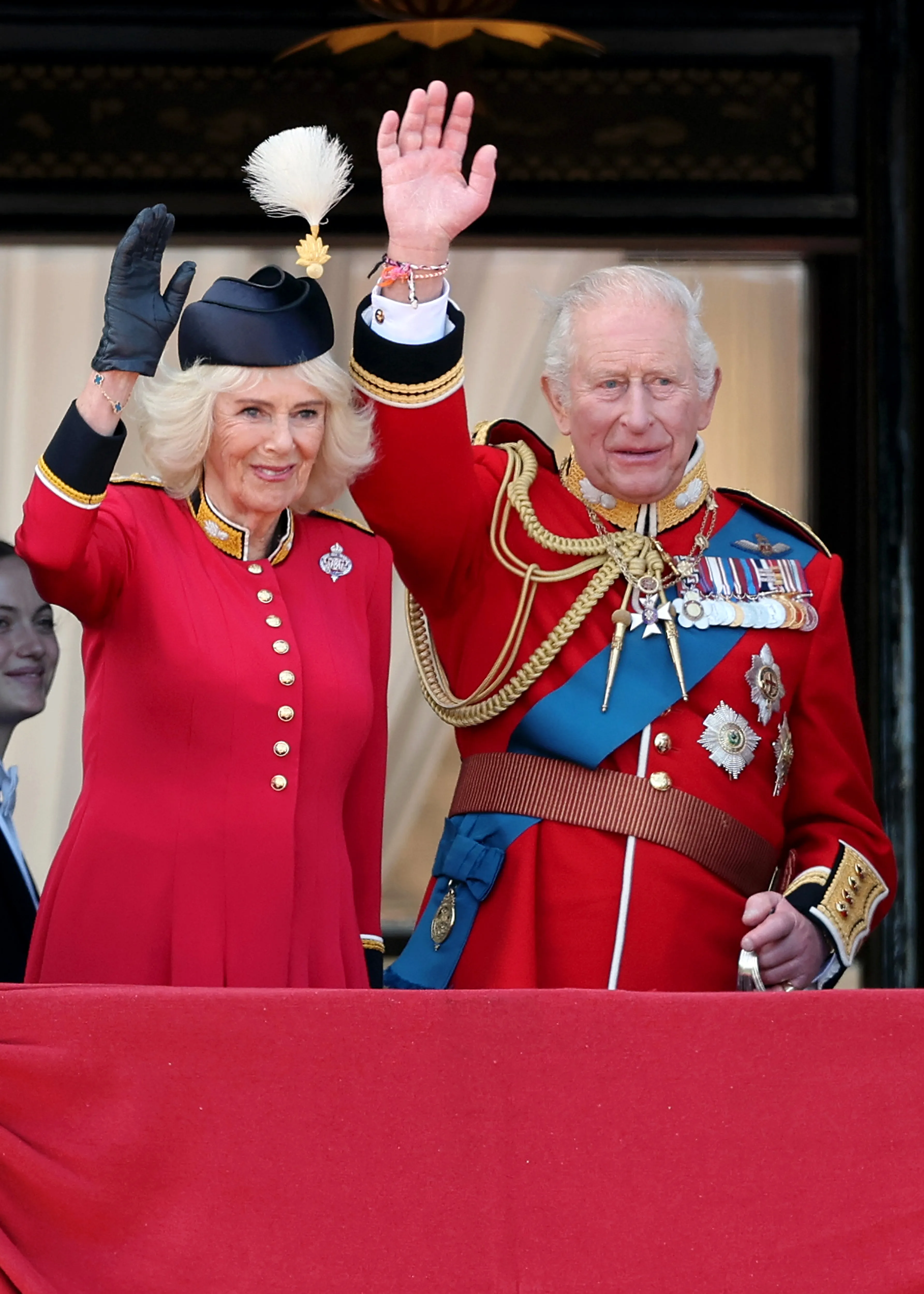 Queen Camilla and King Charles III waving from a balcony during Trooping The Colour.