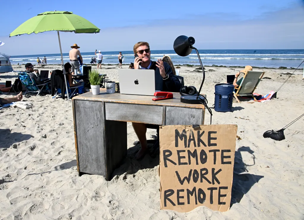 Scott Muirhead, remote work event organizer, at a desk on Pacific Beach in San Diego, on the phone.