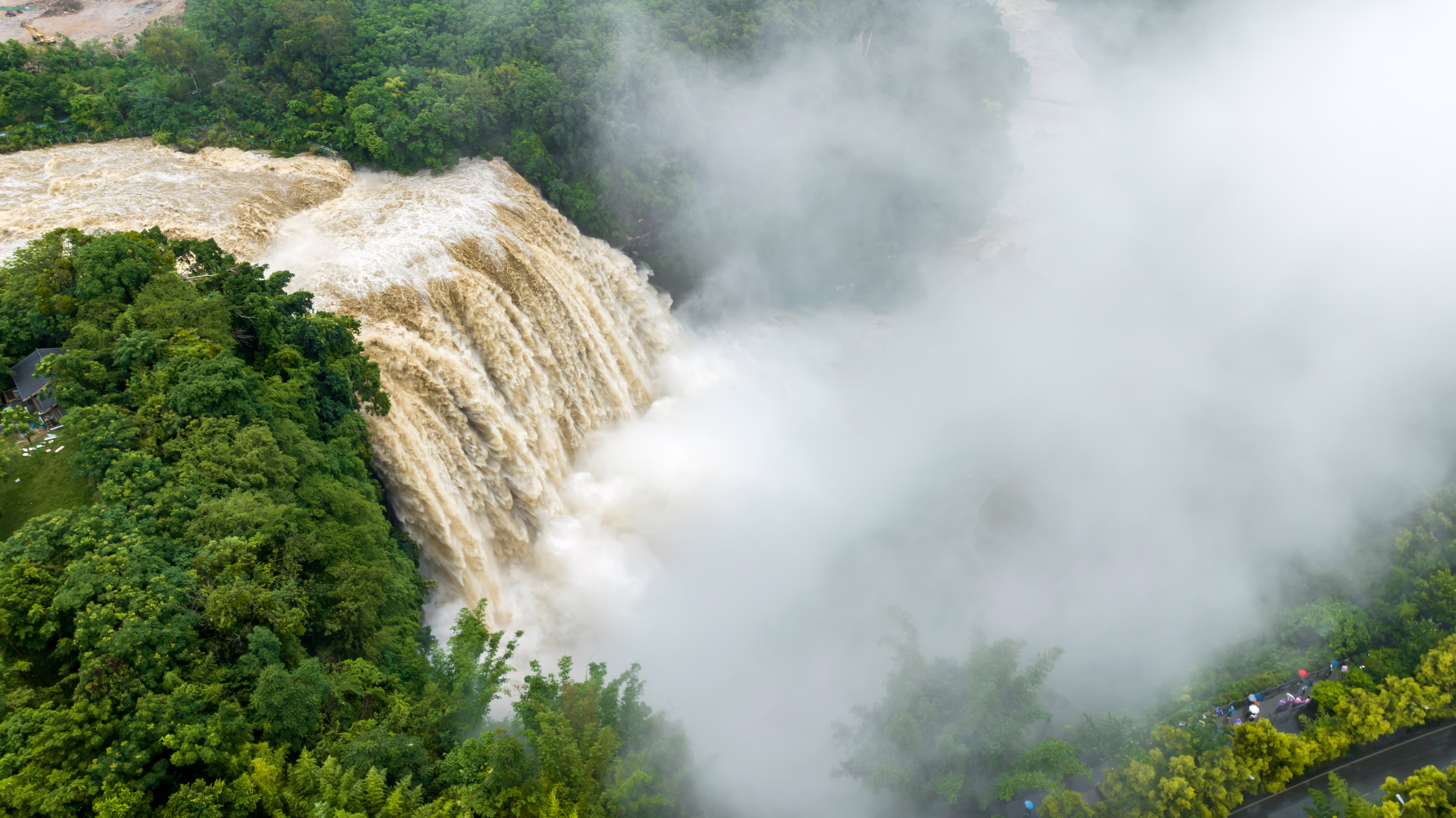 A surging waterfall descends through a forested area.