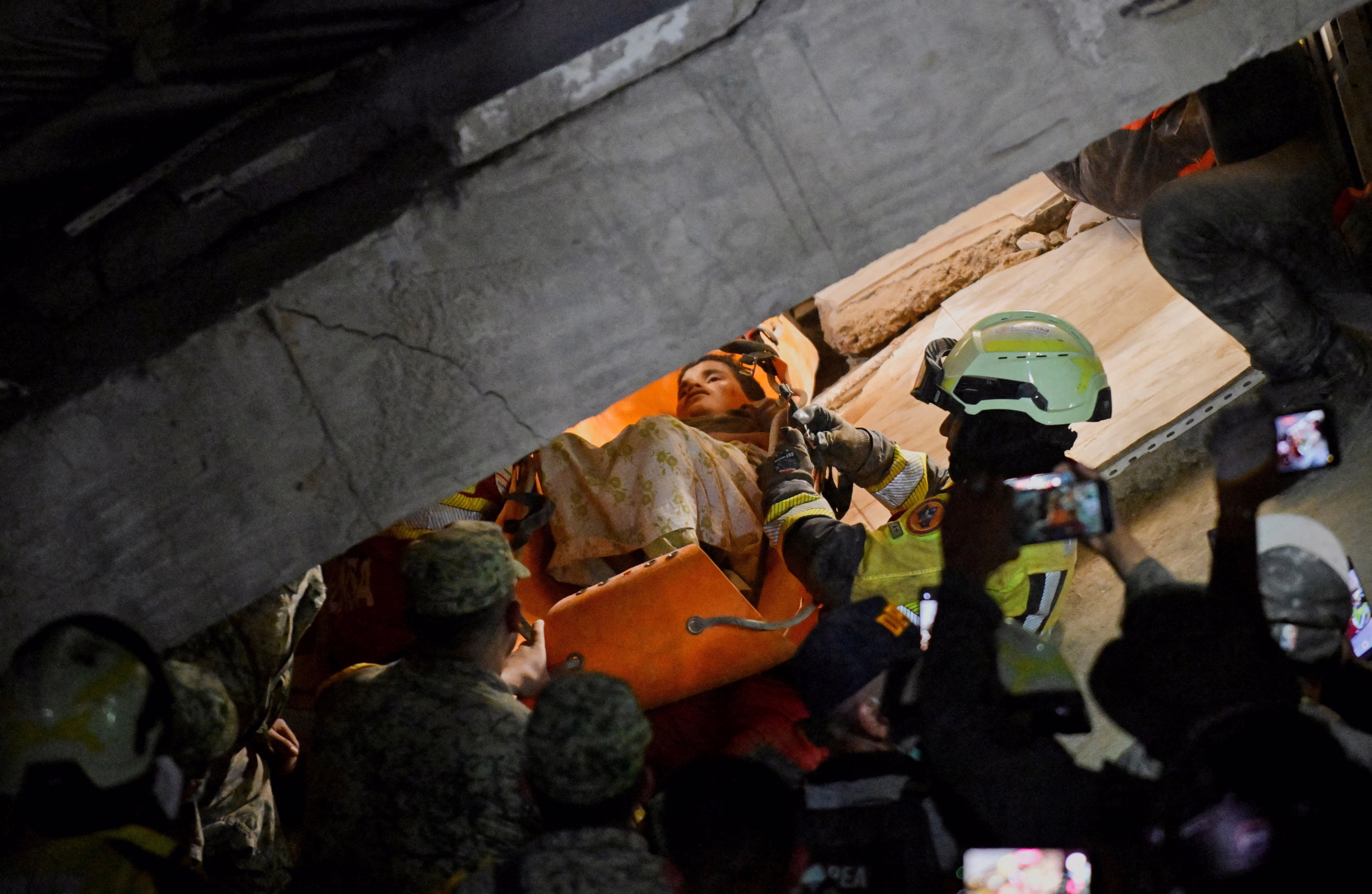Rescuers pull a young person out of the rubble of a collapsed building.