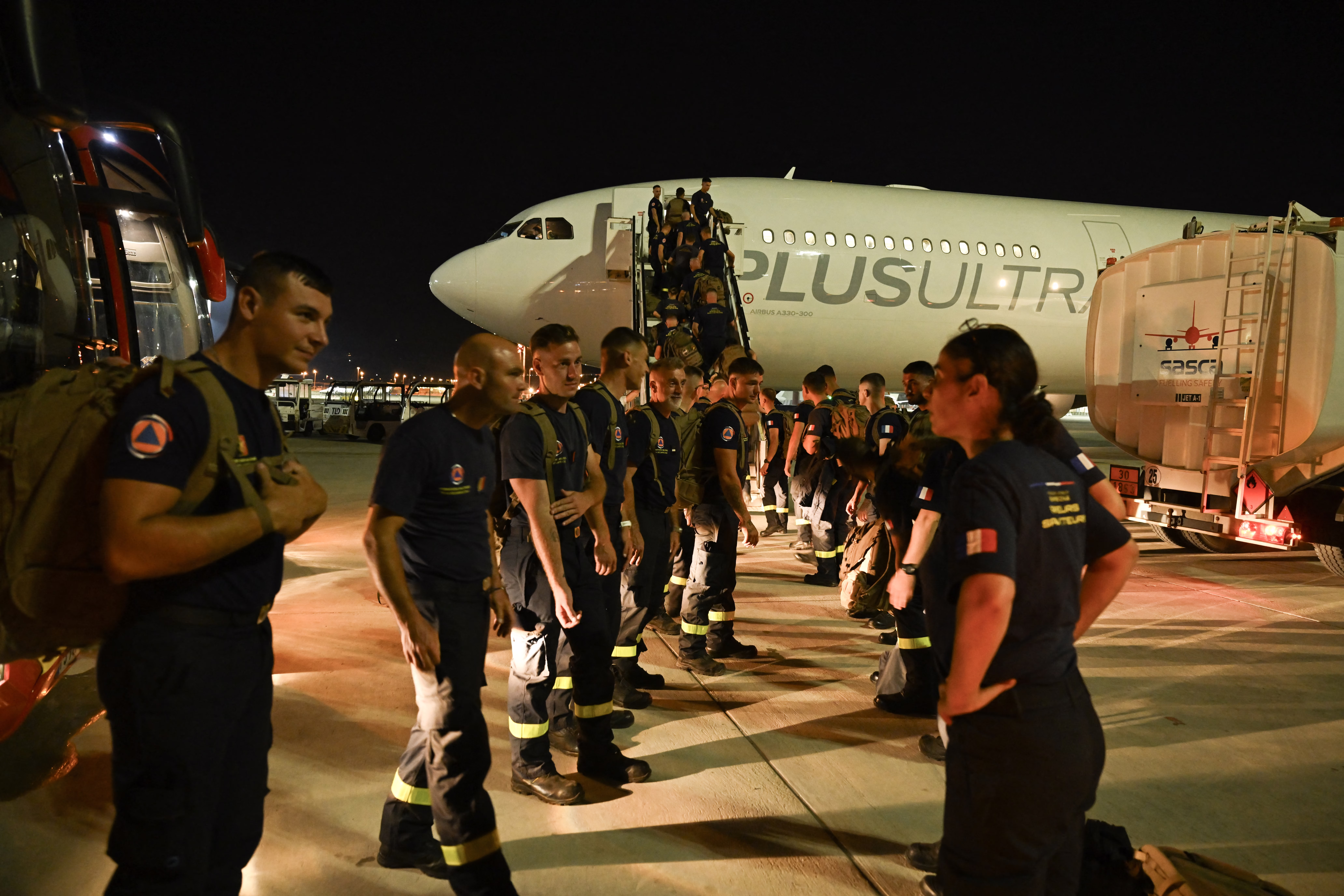Rescue workers gather outside an airplane, preparing to board.