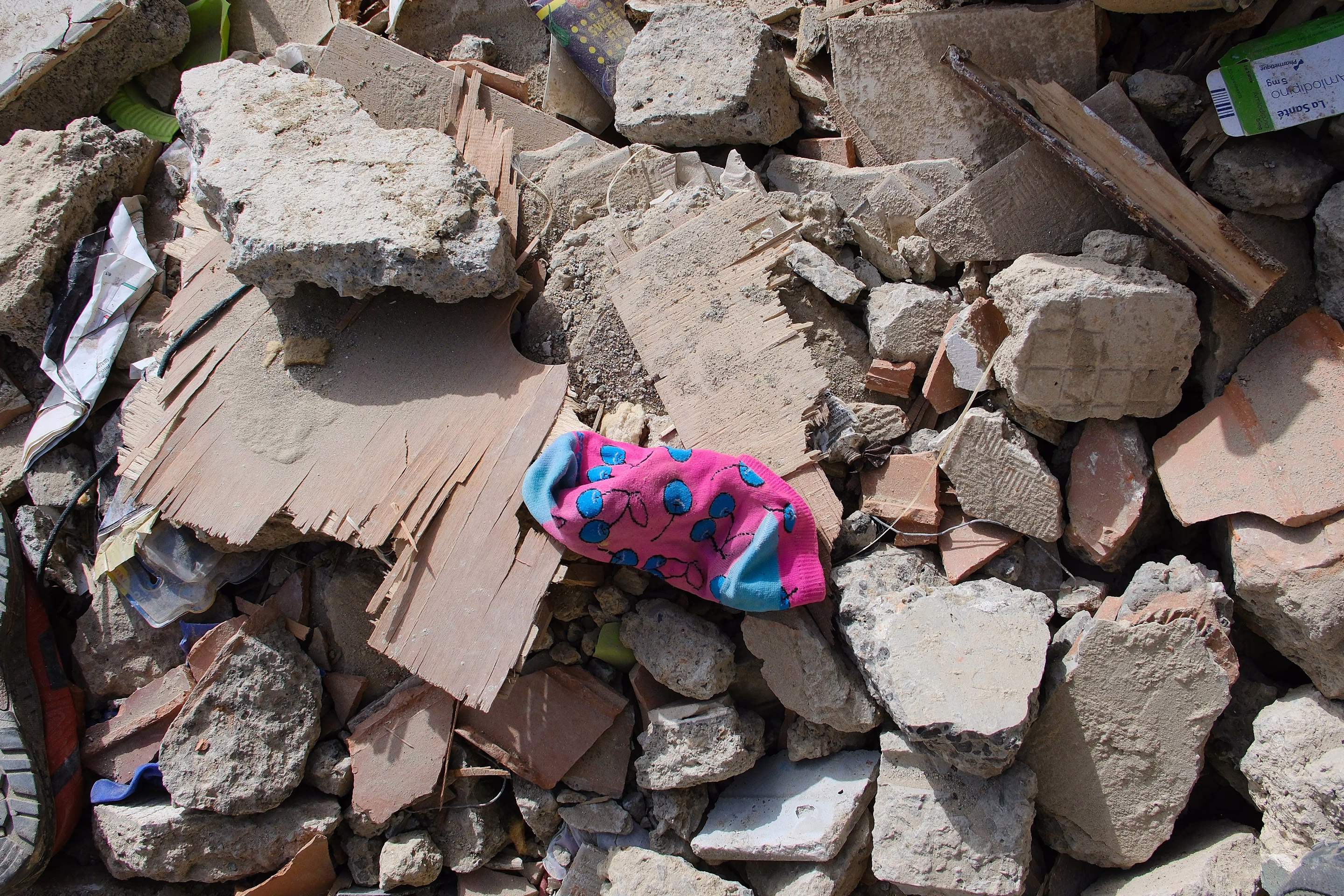a pink sock with blue cherries sits on rubble