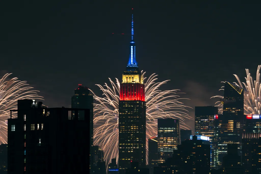 Fireworks erupting around the Empire State Building, lit in red, white, and blue.