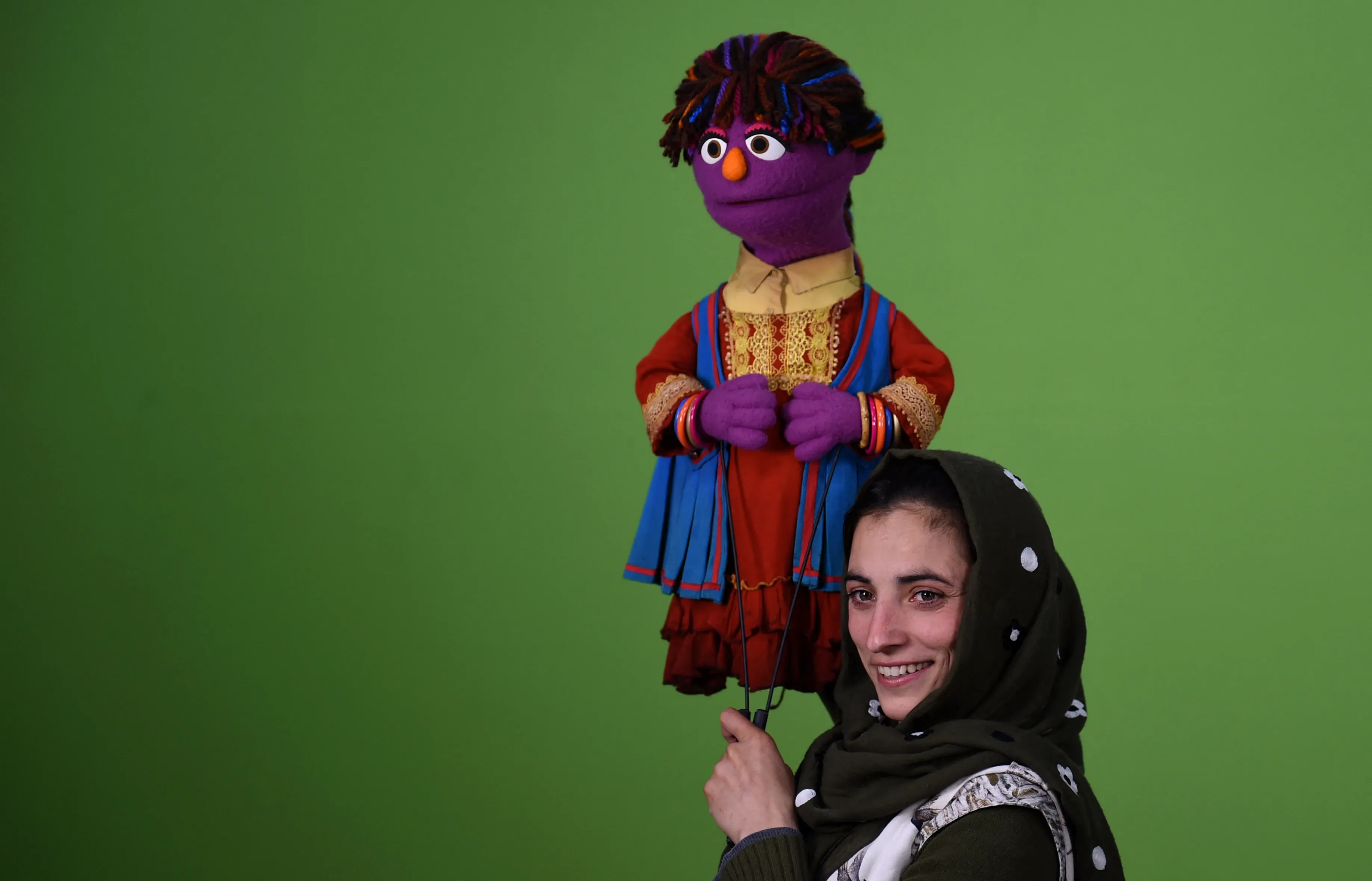 An Afghan puppeteer holds a muppet named