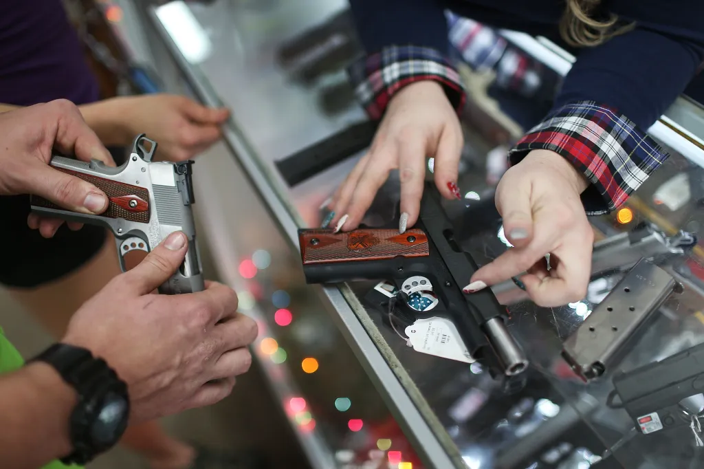 A customer compares handguns before buying one as a Christmas present at the National Armory gun store on Dec. 23, 2015 in Pompano Beach, Florida.