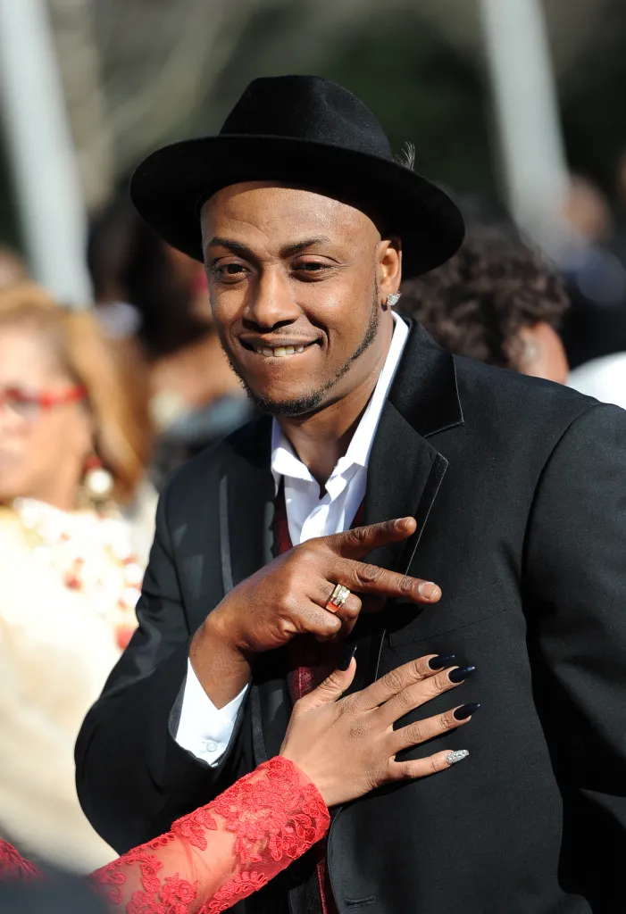 Mystikal smiling and giving a peace sign, with Rocsi Diaz's hands touching his chest.