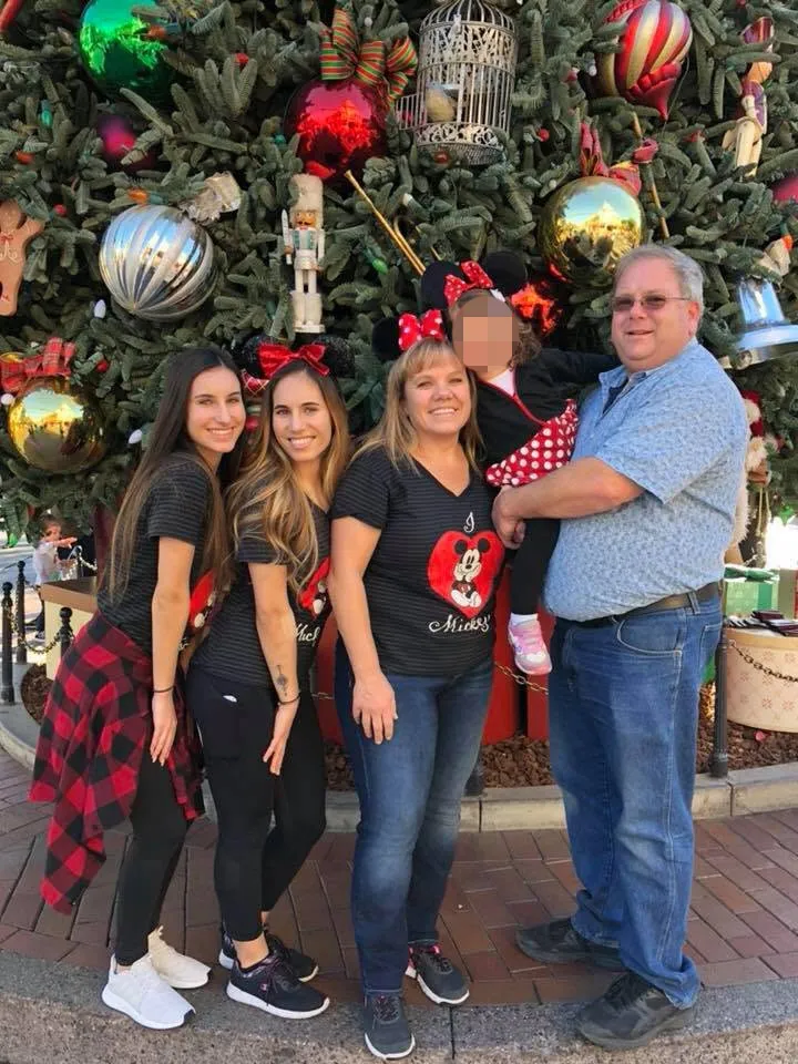 Amanda Phillips, Ashley Phillips, Lesley Plank Jonkey, and Jeff Jonkey pose in front of a Christmas tree.
