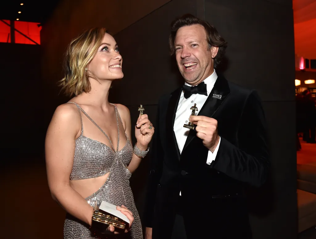 Olivia Wilde and Jason Sudeikis holding Oscar statuettes.