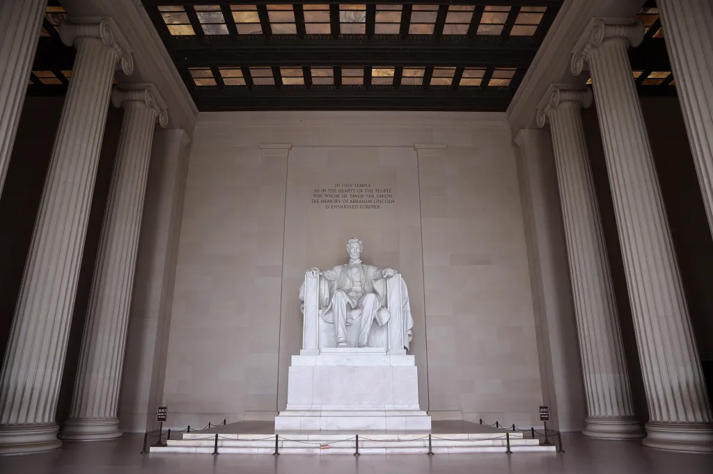 A view of the Lincoln Memorial with the Abraham Lincoln statue and text on the wall, showing the memorial empty of tourists.