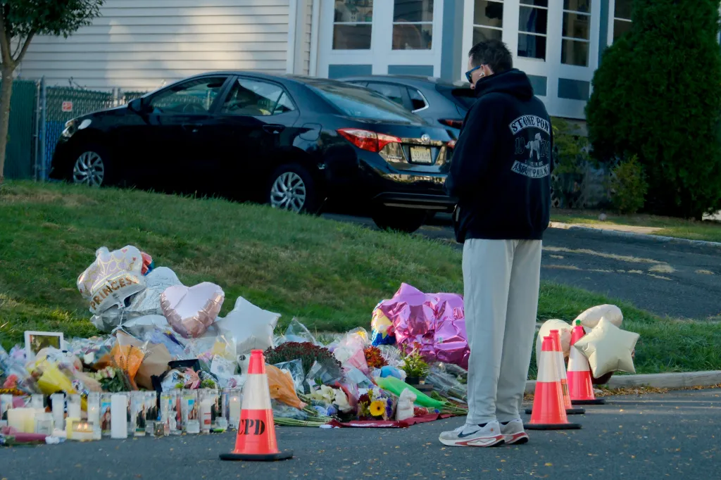 A person prays at a memorial of flowers, candles and photographs for the two teen girls killed in the hit-and-run crash in Cranford, NJ, on Oct. 2, 2025.