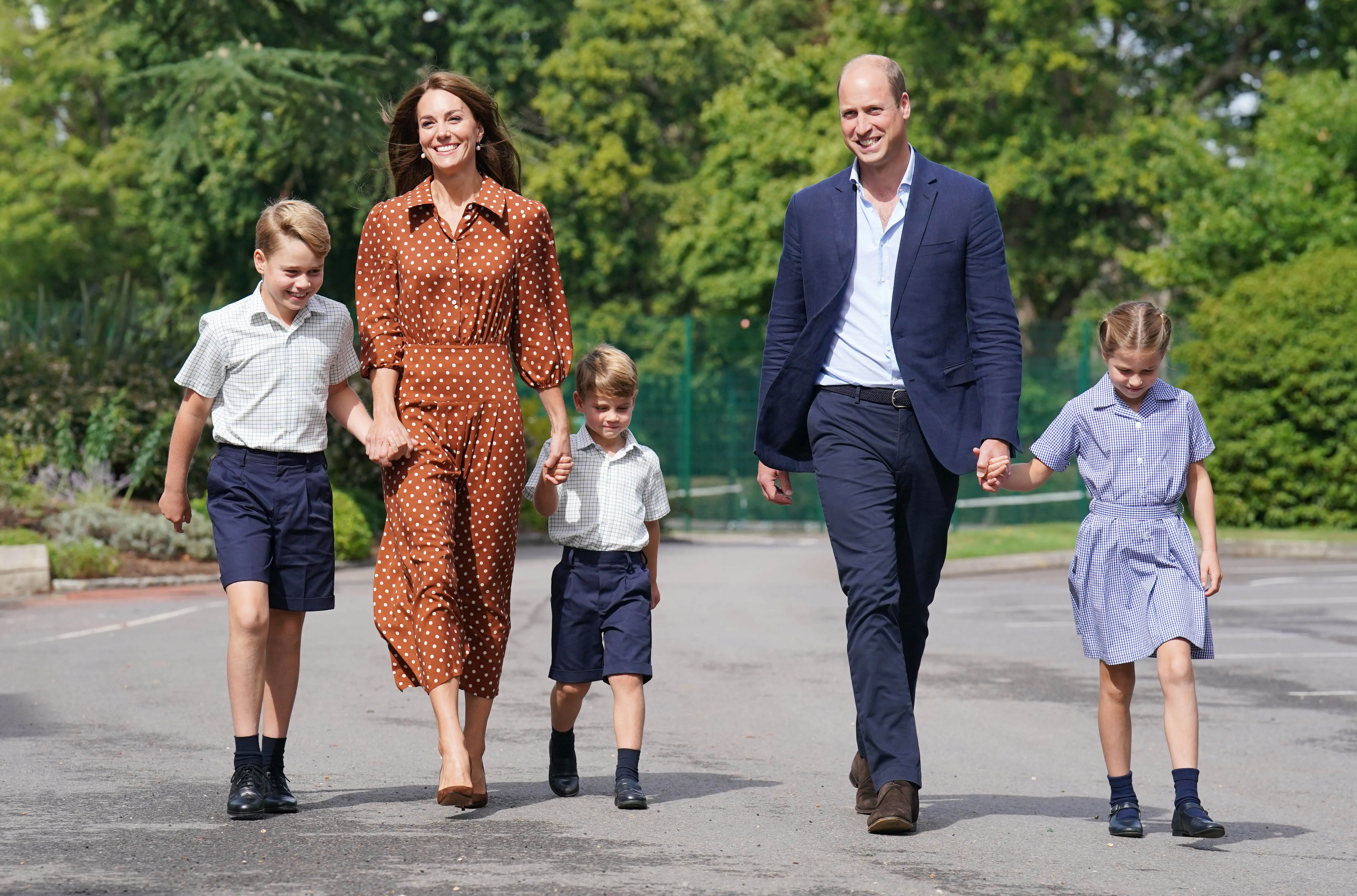 Prince William and Kate Middleton holding hands with their children, Prince George, Princess Charlotte, and Prince Louis, as they walk to school.